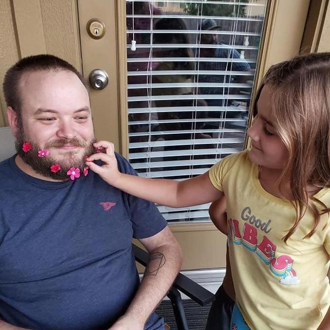 Sayra's niece adding flowers to Cade's beard.