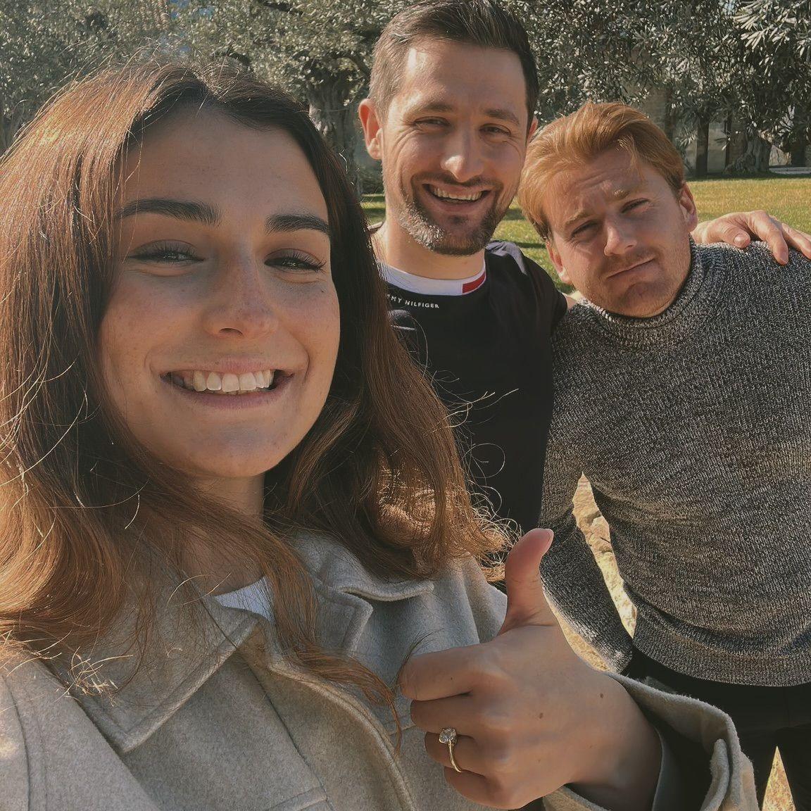 Char showing her thumb to Nick & Jake in a park.