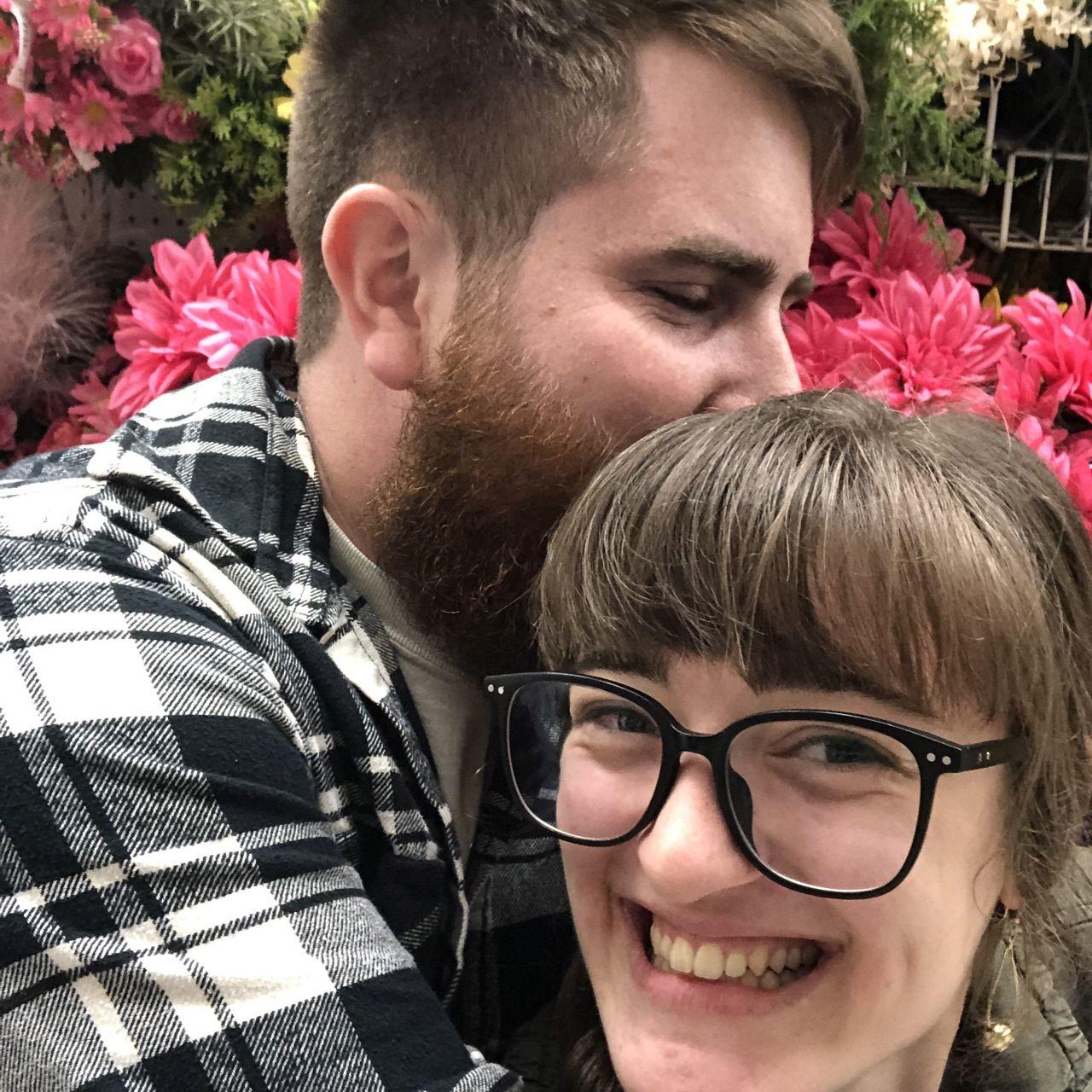 Mini date night taking photos in front of florals at Joann