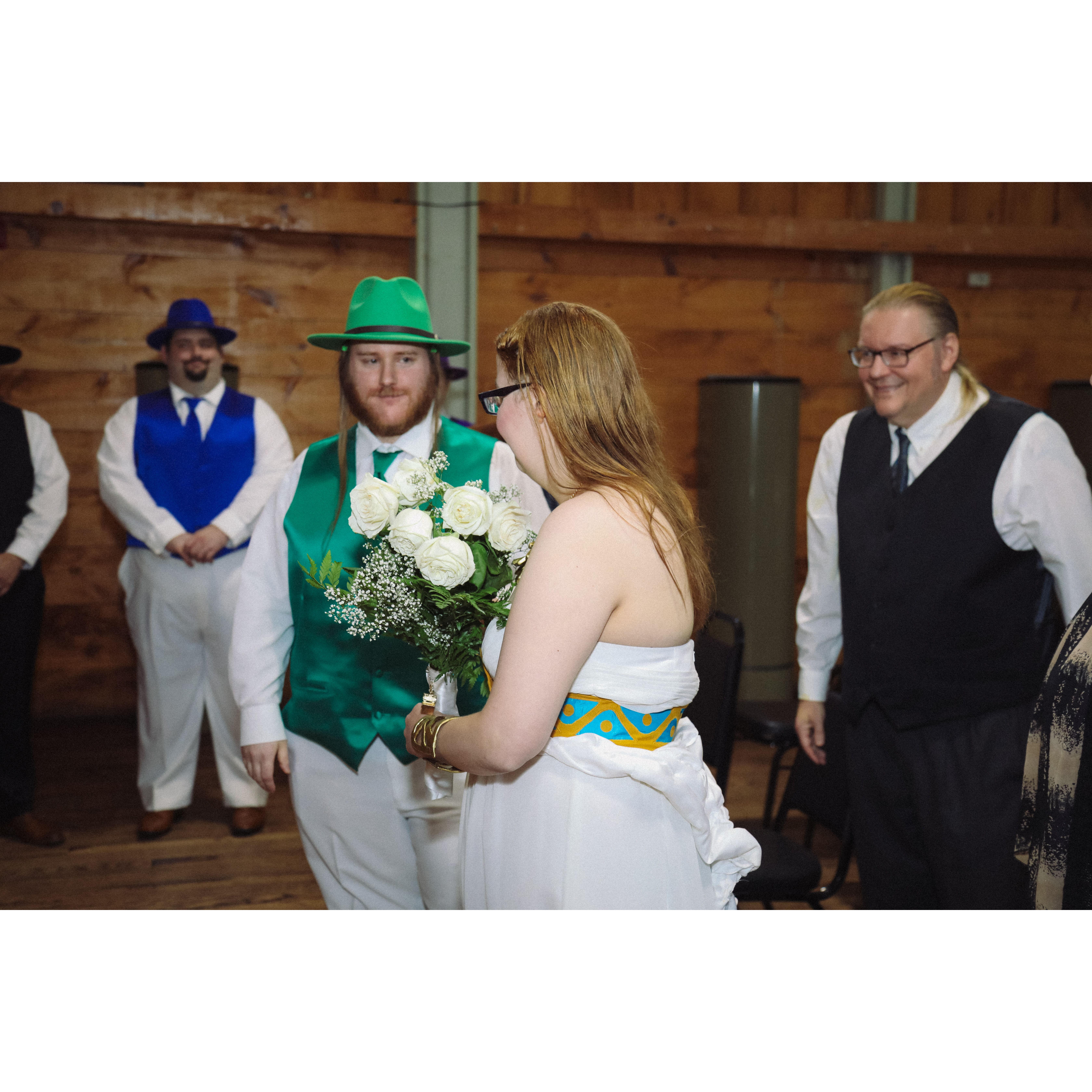 during the ceremony, Herb with the groomsmen looking at Sara approaching the wedding arch with Tim