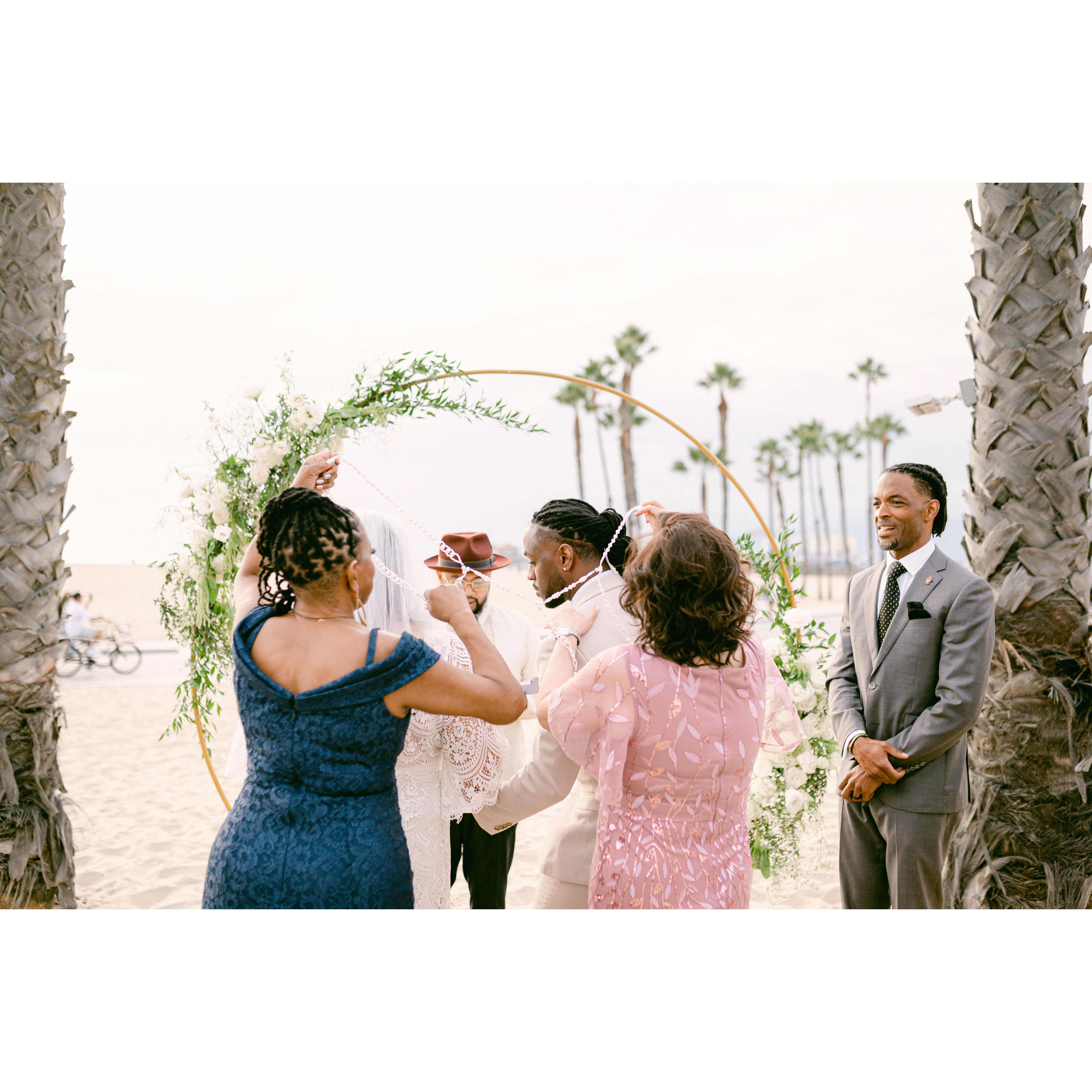 Mama Moore & Mama Tongol putting a wedding  cord around the couple to carry on a Filipino wedding tradition.