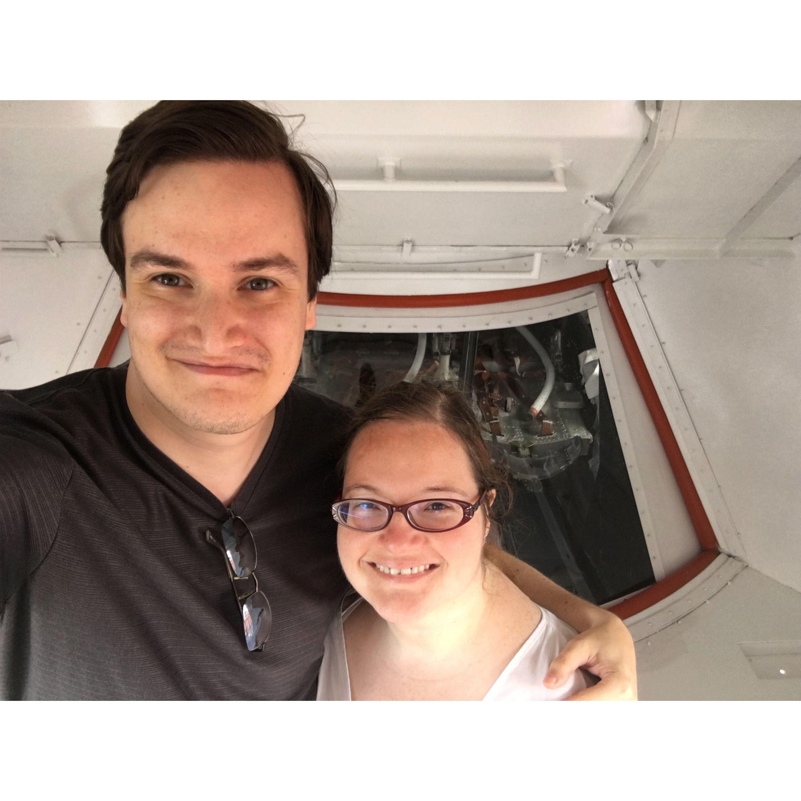 Olivia and zac smiling, posing in front of the Apollo capsule at Kennedy Space Center.