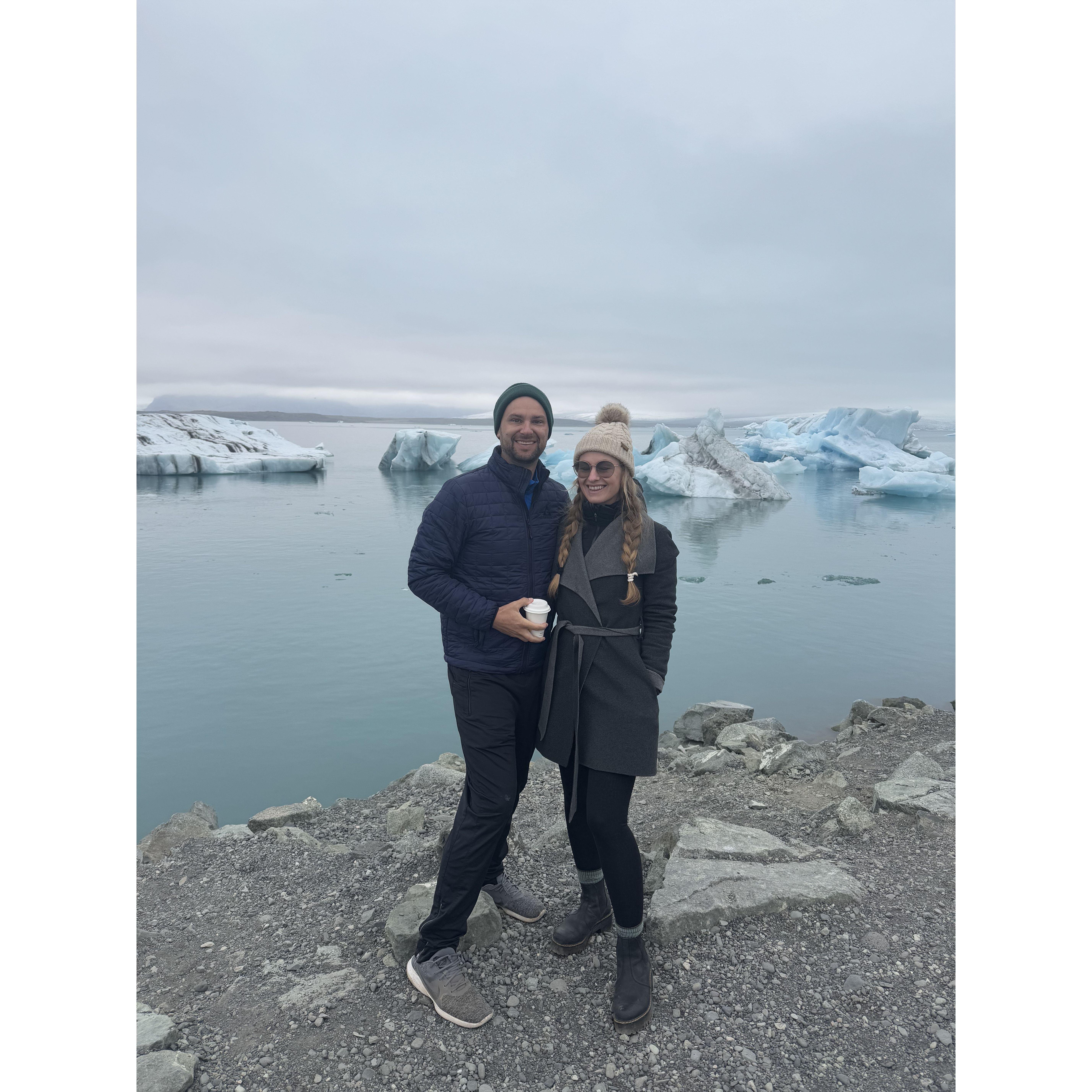 Iceburgs floating behind the newly engaged couple at Glacier Lagoon.
