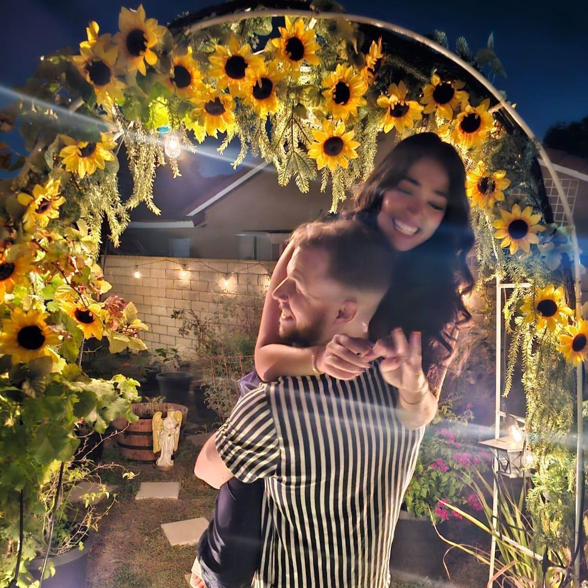 Newly engaged under a sunflower arch