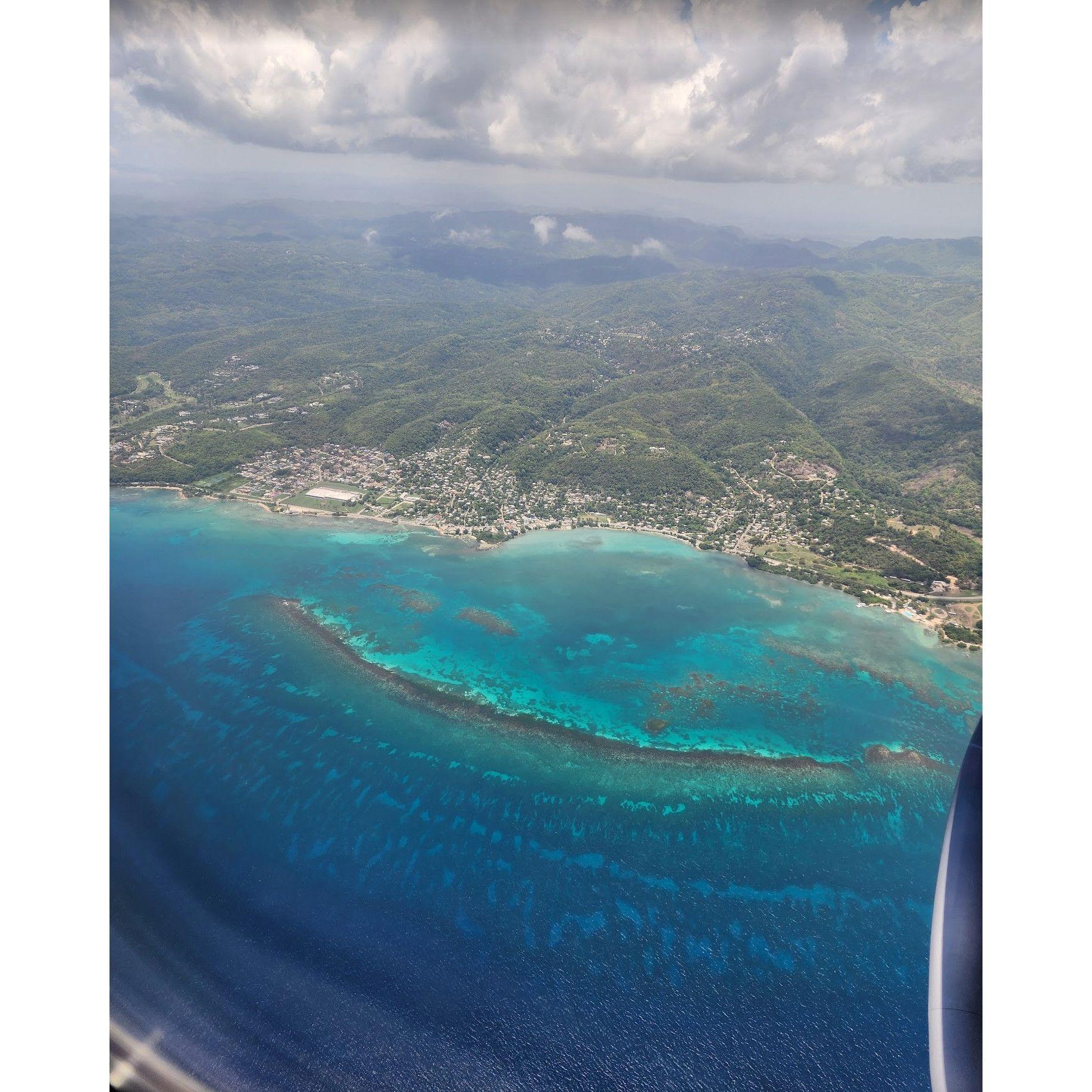 Flying over Jamaica, where the mountains kiss the clouds and the sea sparkles like a dream.