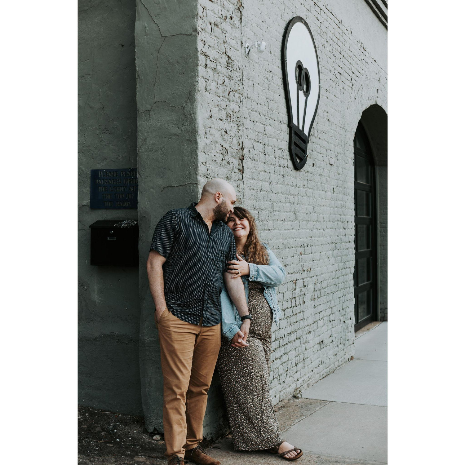 Candid engagement photo on a cool wall in downtown Greensboro