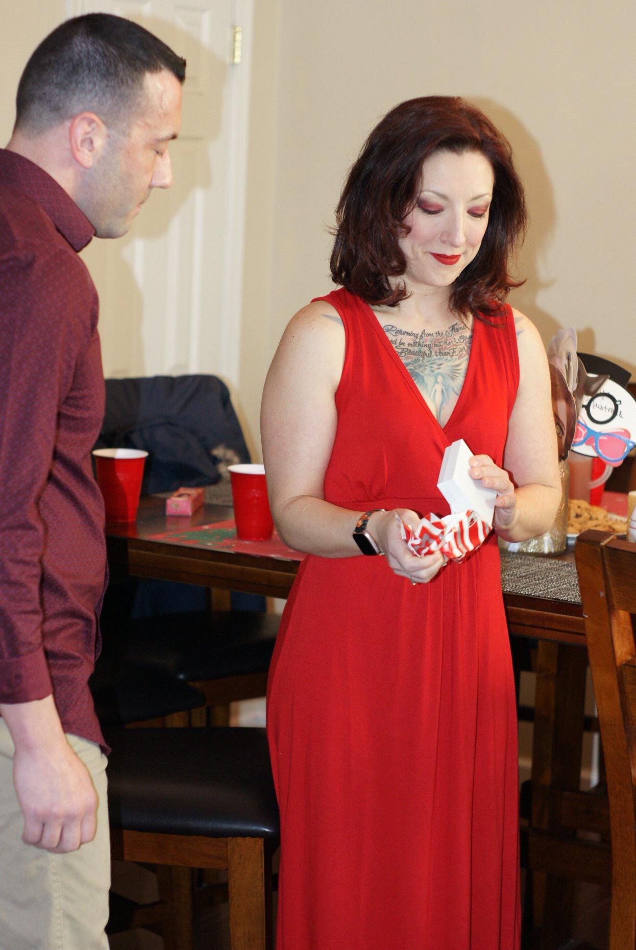 Tina begins to unwrap the gift.