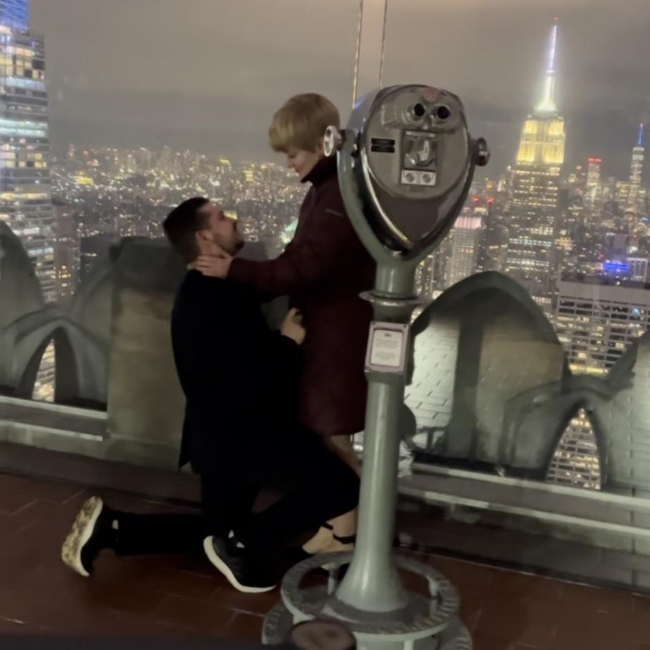 Cam proposed on the top of the Rockefeller Center in NYC, and a very nice stranger caught the moment for us!