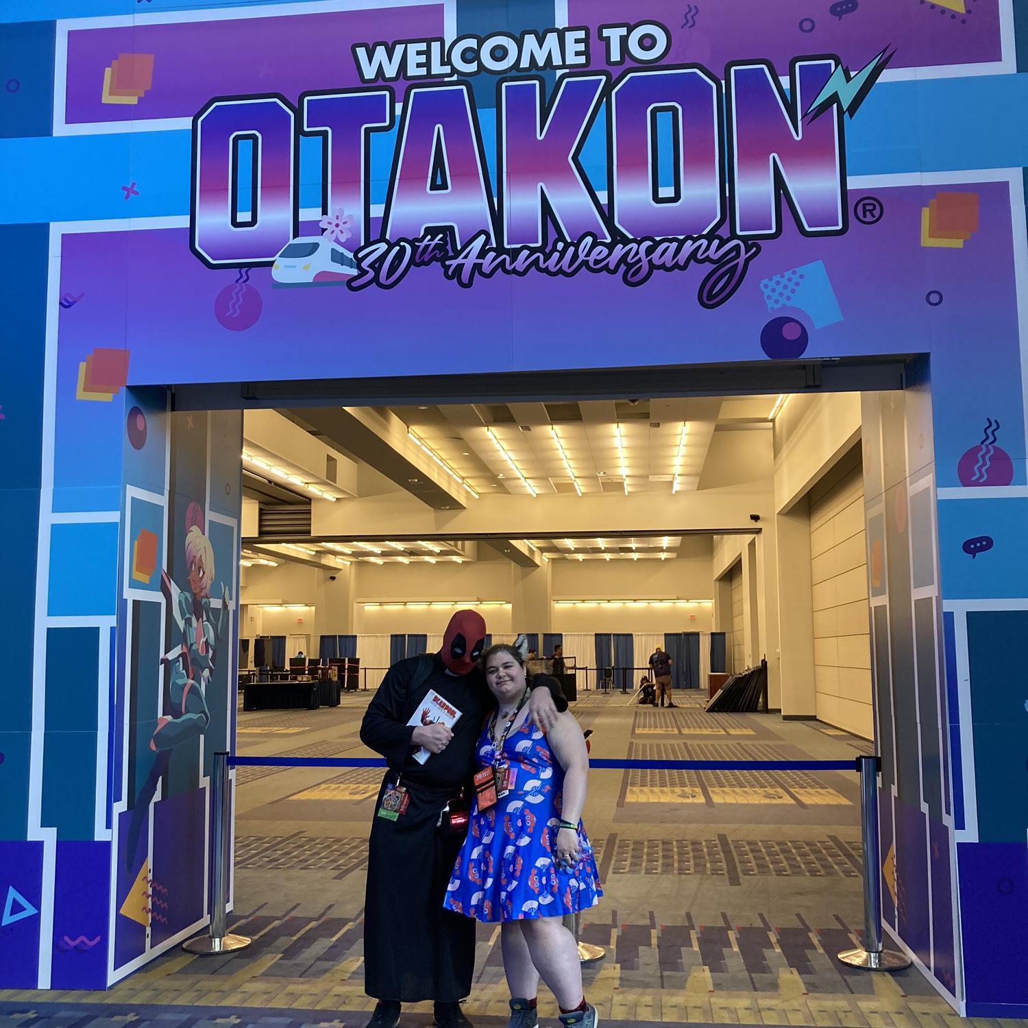 Priest-pool and Otakon mascot, under the 30th anniversary arch