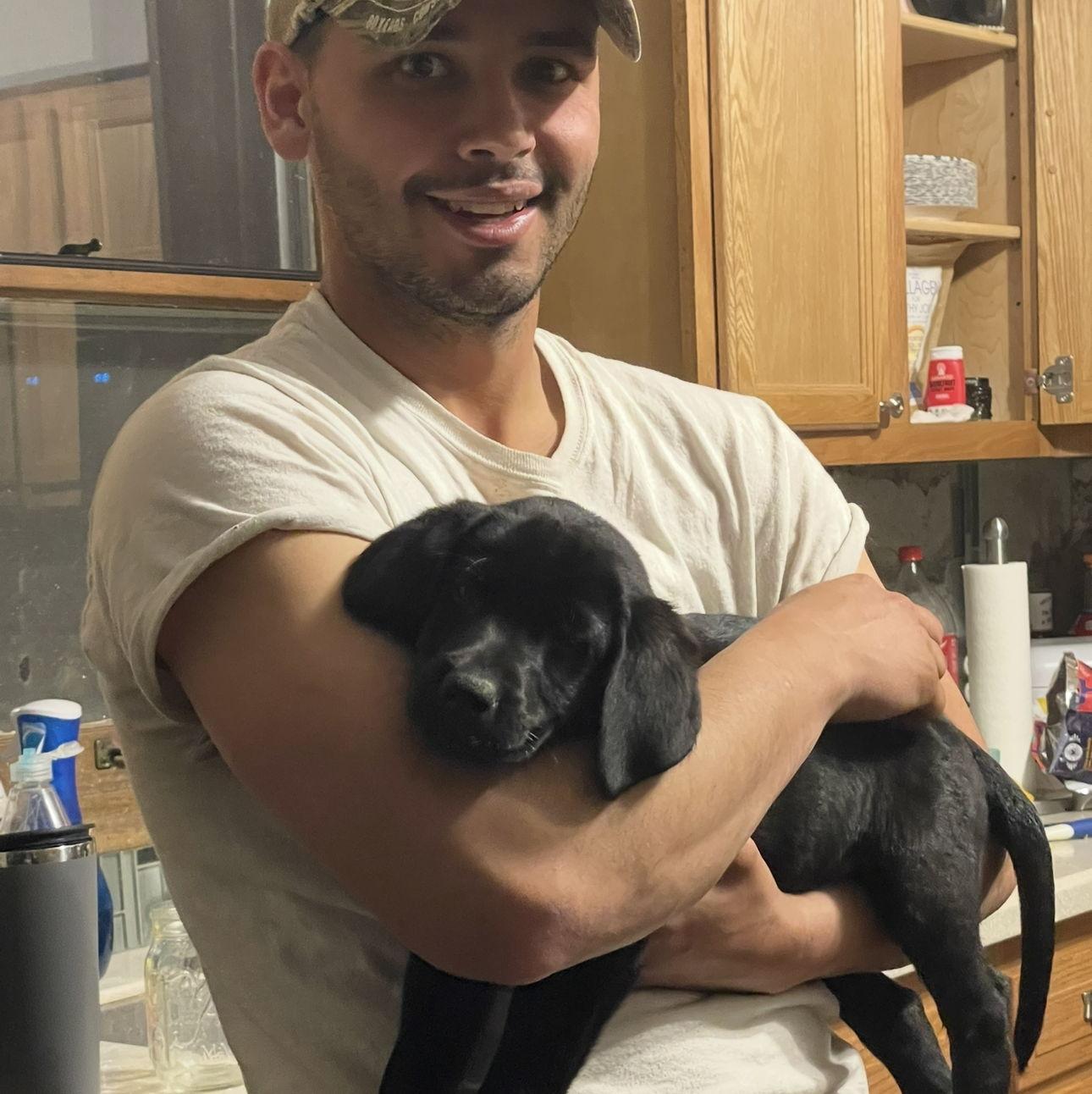 Ember as a puppy with Aaron in 2023