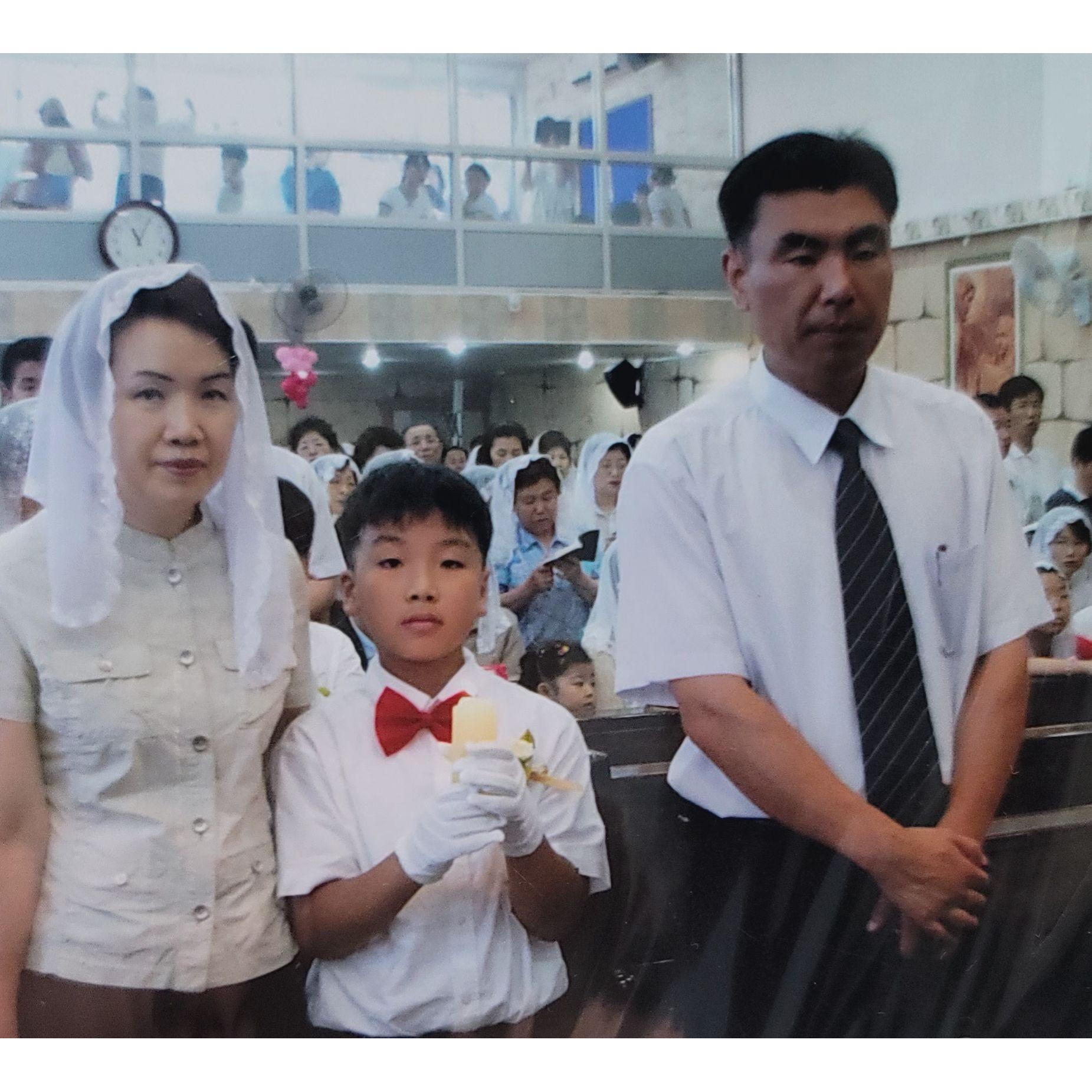 Jinhwan with his mom and dad during a ceremony at church, probably his First Communion. 성당에 진환이가 부모님과 함께 있는 사진이에요. 아마도 이날 첫 영성체를 받는 날이었을 거예요.