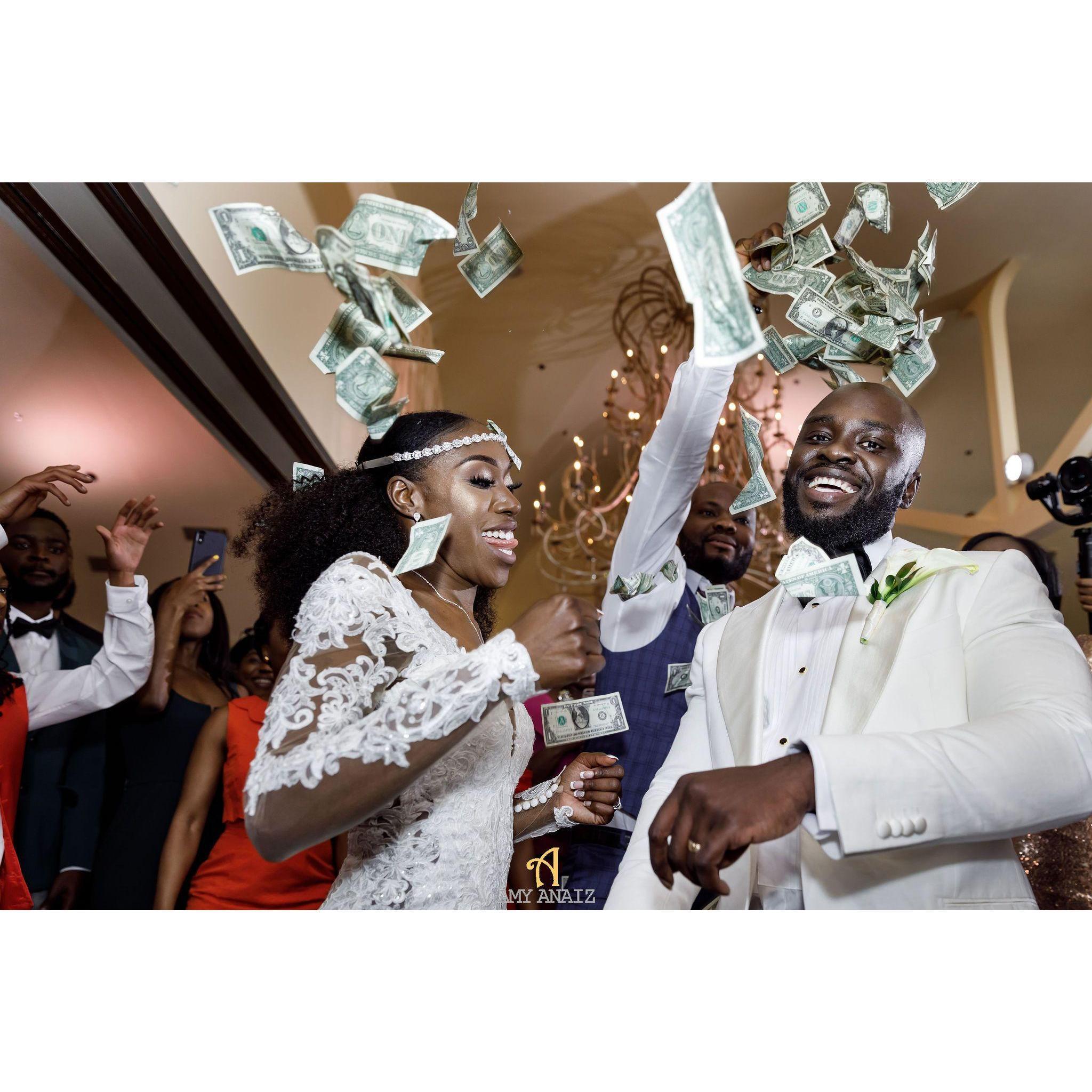 Money Spraying in many African cultures symbolizes a showering of happiness, good fortune, and a display of affection for the couple during their first dance.