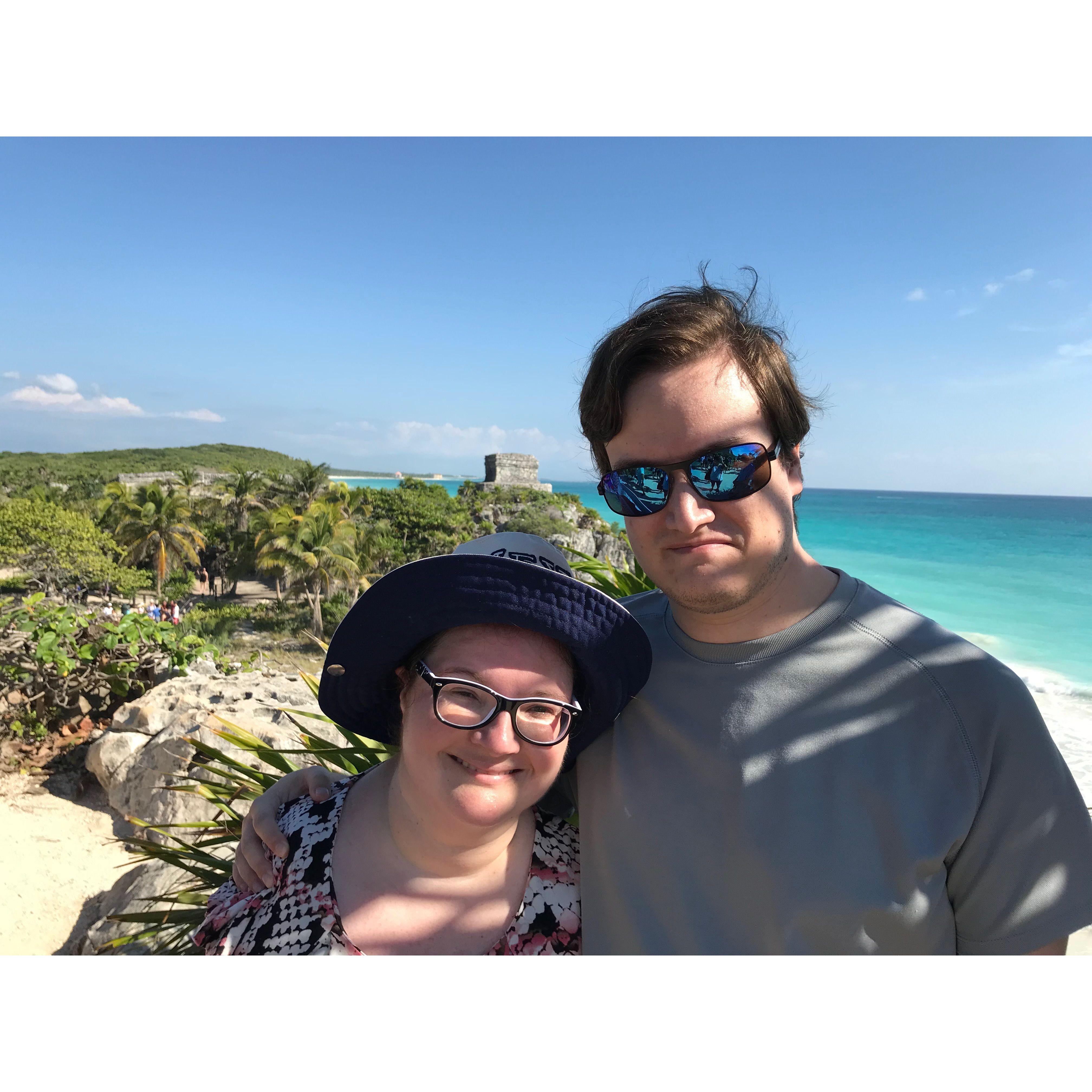 They smile with a beautiful island scenery behind them at Tulum in Mexico.
