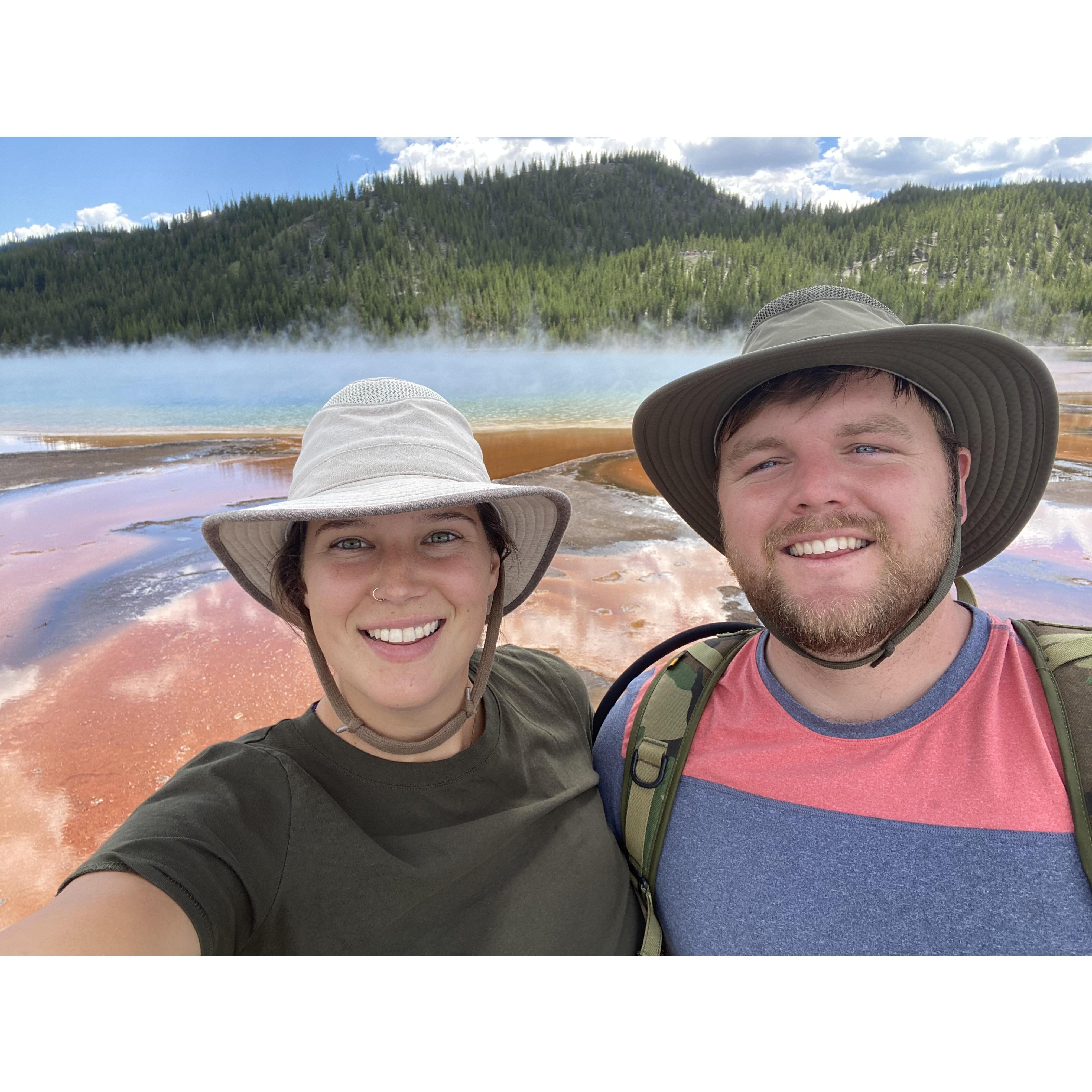 Megan and Russell's first road trip in their van to Yellowstone National Park, standing next to Grand Prismatic Spring