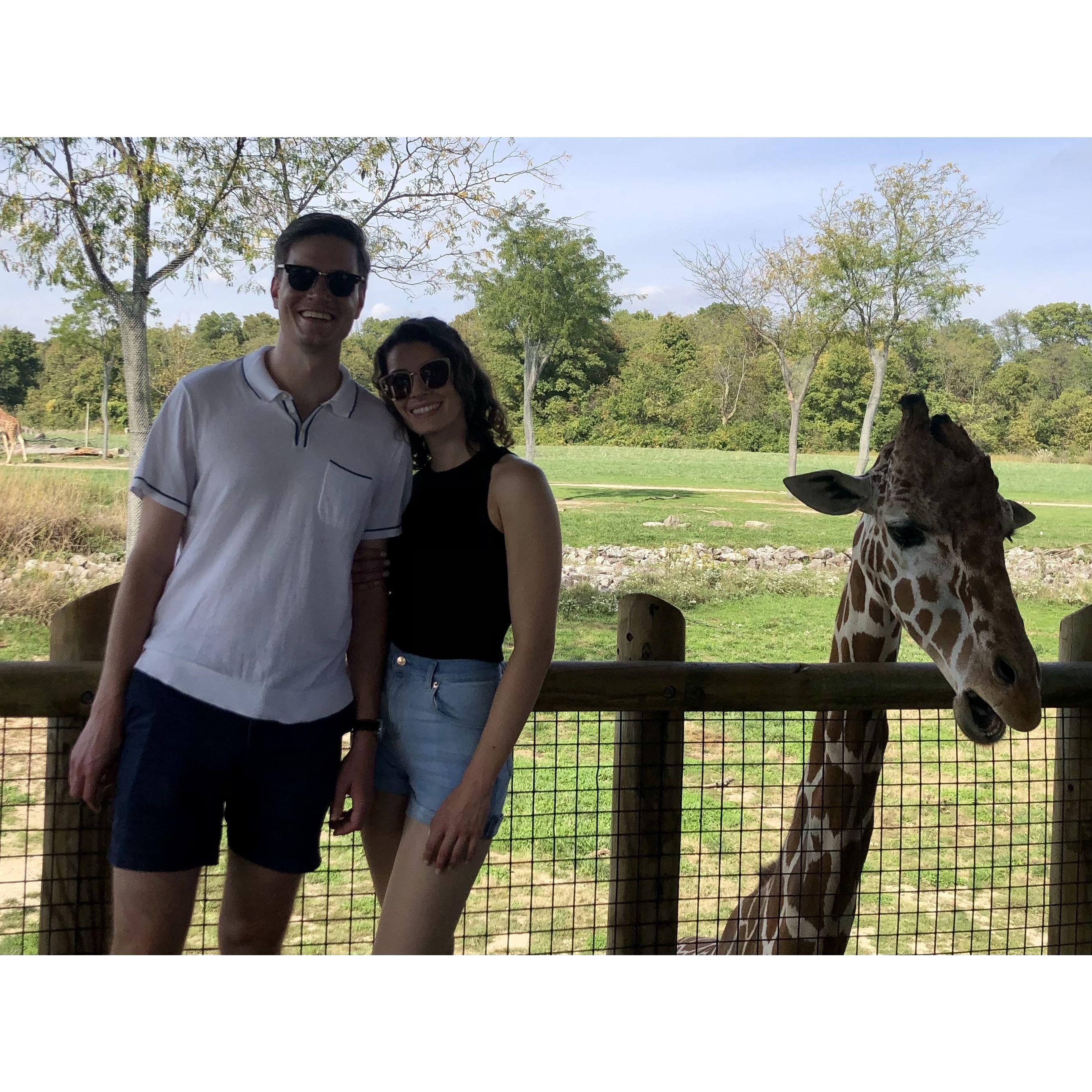 Two super tall people and an even taller giraffe