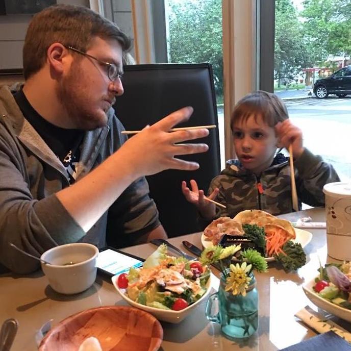 Keven teaching Greg to use chopsticks