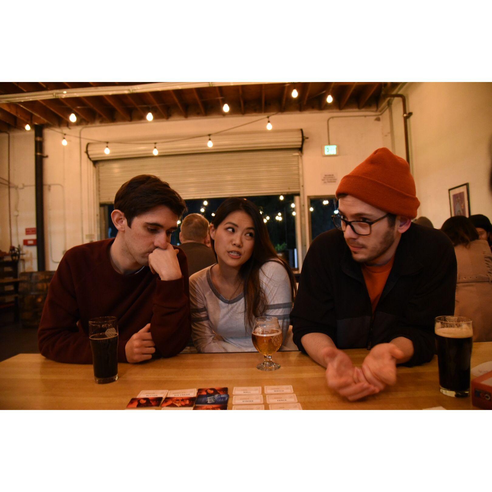 A heated moment in the middle of a game of Codenames at Three Weavers Brewery in LA with Drew (groomsman). Among their LA friends, honor and status was won and lost over Codenames.