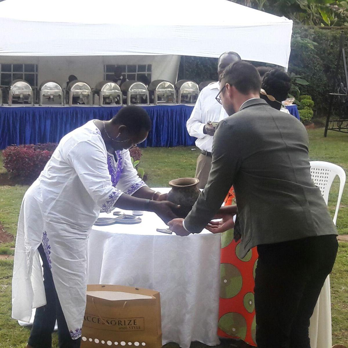 The couple receiving a pot to cook in. This was presented by Irene's fathers sister, Justice Rose Ougo, with advise to cook daily, for her future husband .