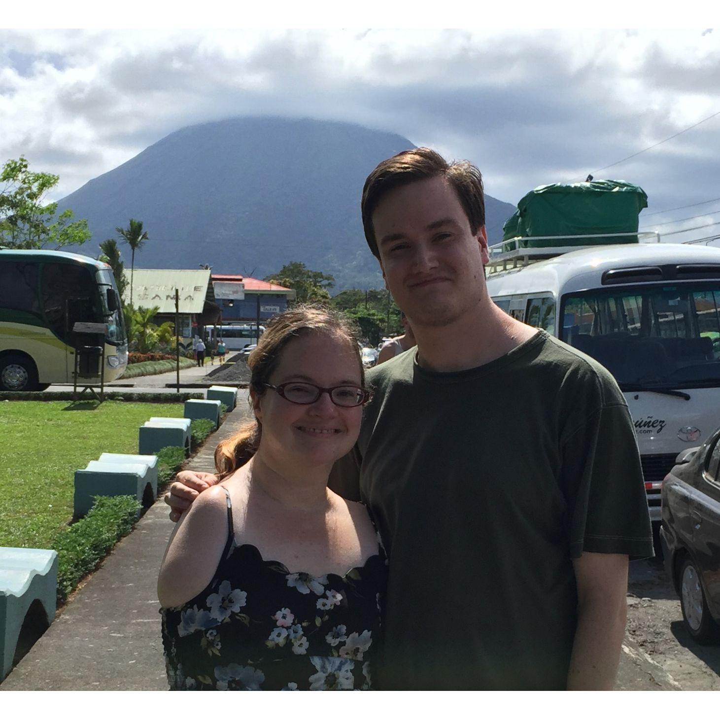 Olivia and Zac in La Fortuna, Costa Rica, posing and smiling in front of a large mountain