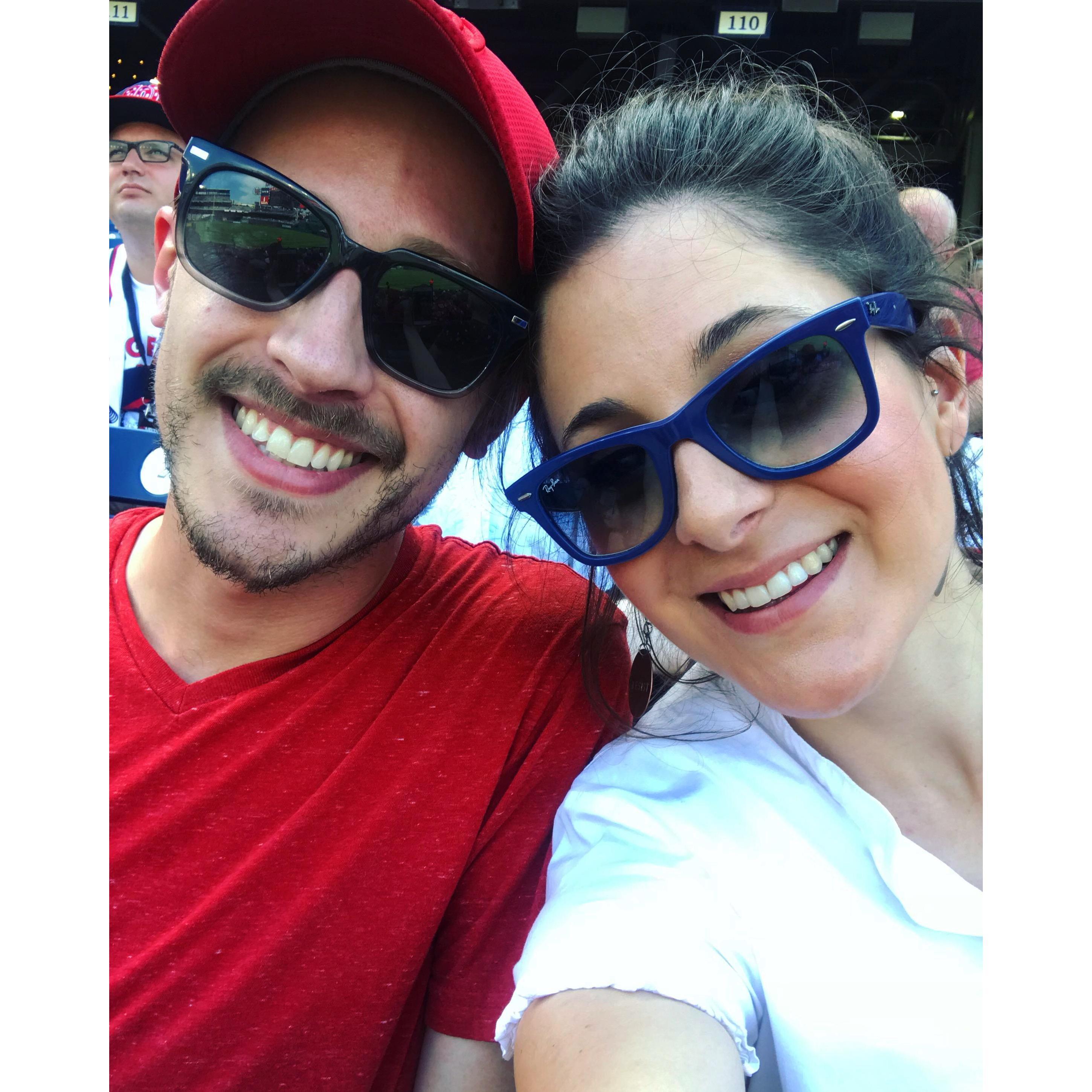 Nats game. Man with glasses watches intently over Cameron's shoulder.