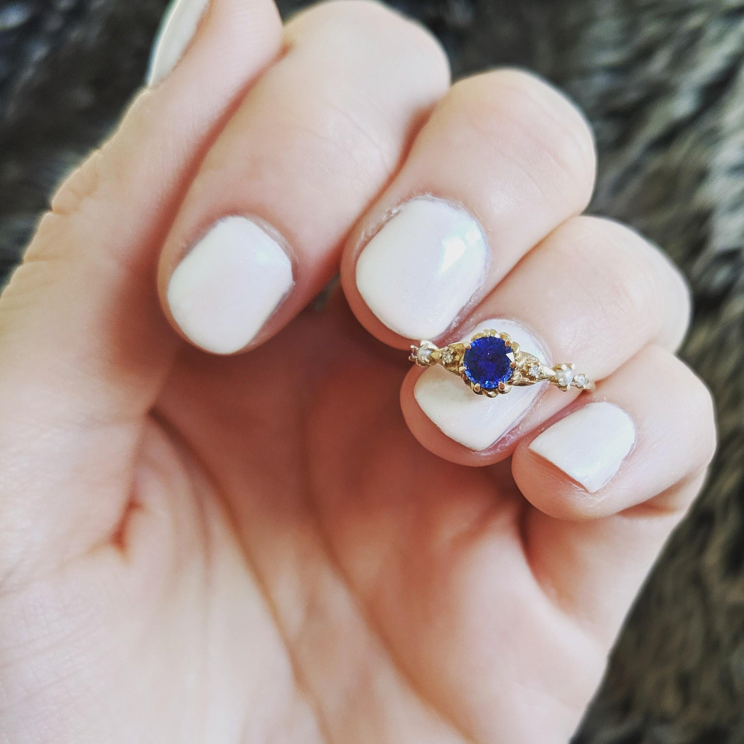 Our engagement ring is created with four small diamonds, two little pearls and the center stone is a beautiful deep blue sapphire which happens to be Justins Birthstone.