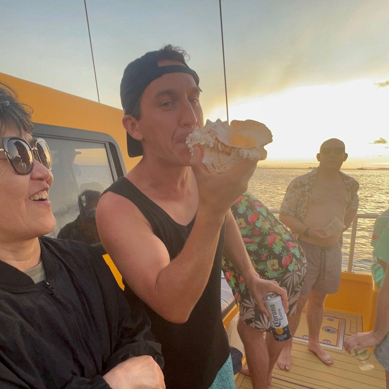 Hawaii sunset booze cruise. Adam proving he can play the trumpet via a conch shell...