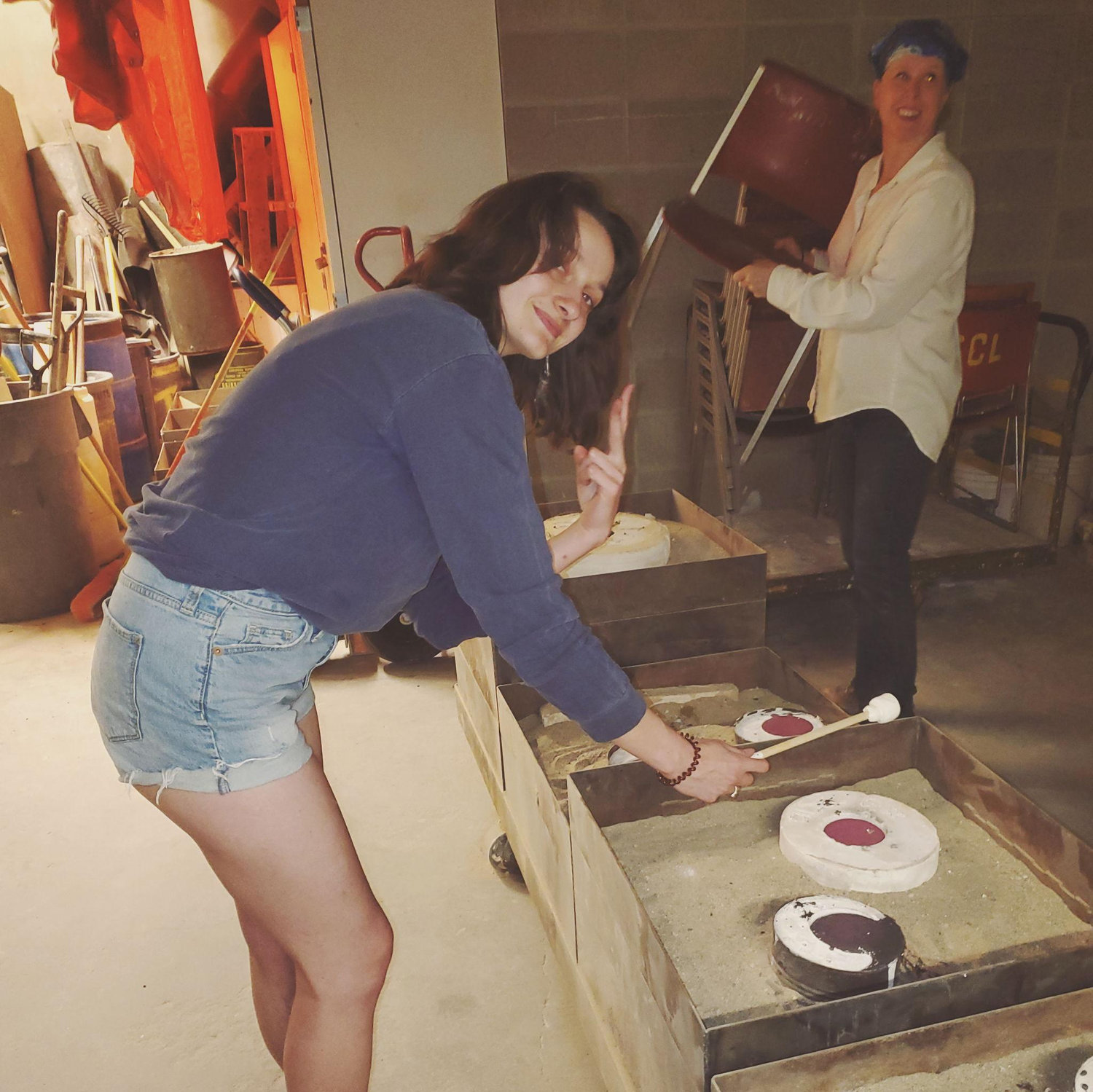 A photo of Paige roasting marshmallows over red hot bronze casting molds that were just poured.