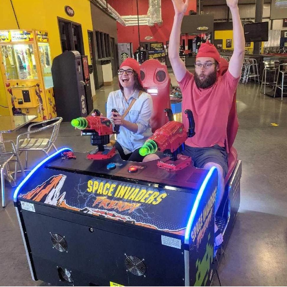 Playing Space Invaders in our under-helmet hats while waiting to drive go karts