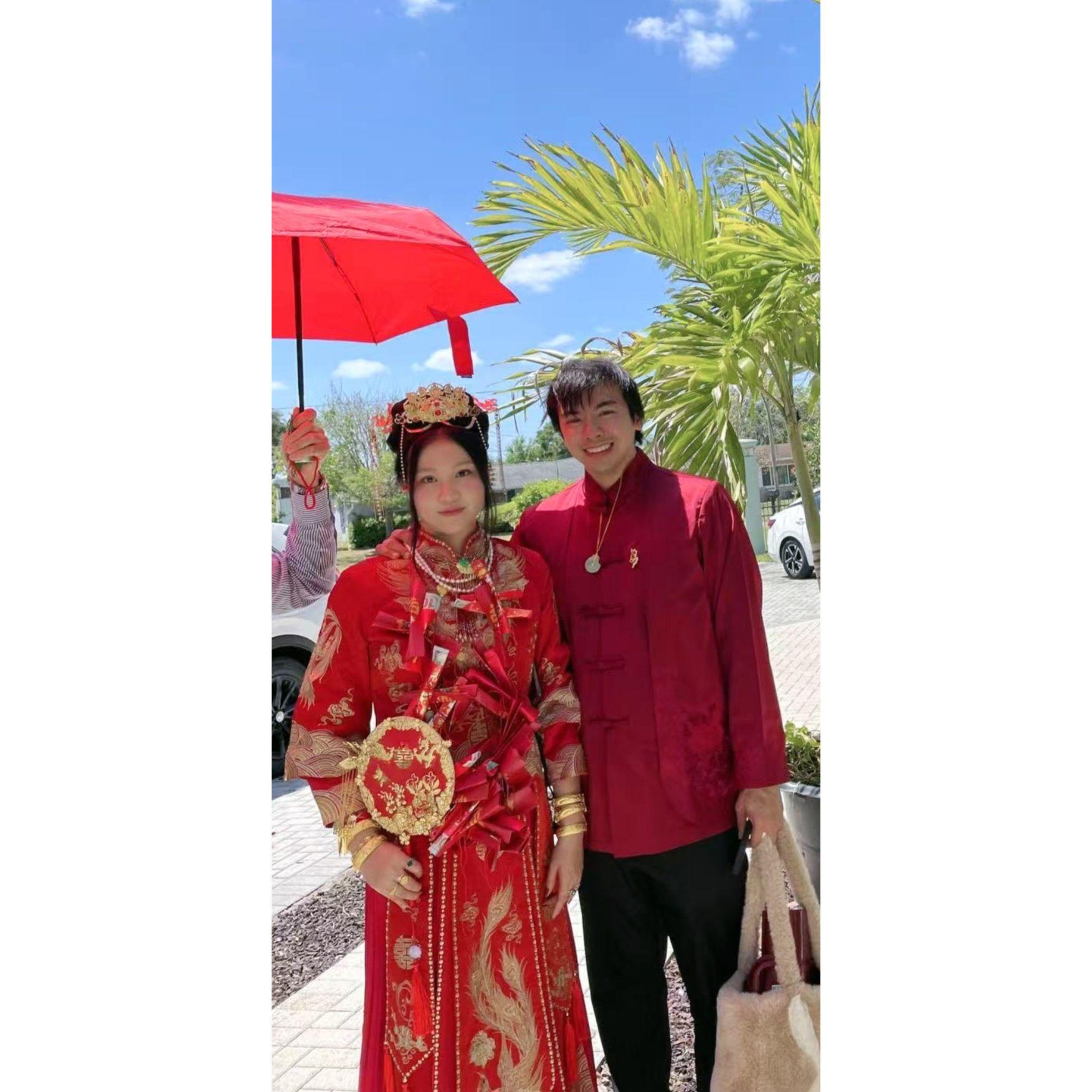 Beneath the protection of the red umbrella, the bride and groom arrive at the ceremonial tea party destination.