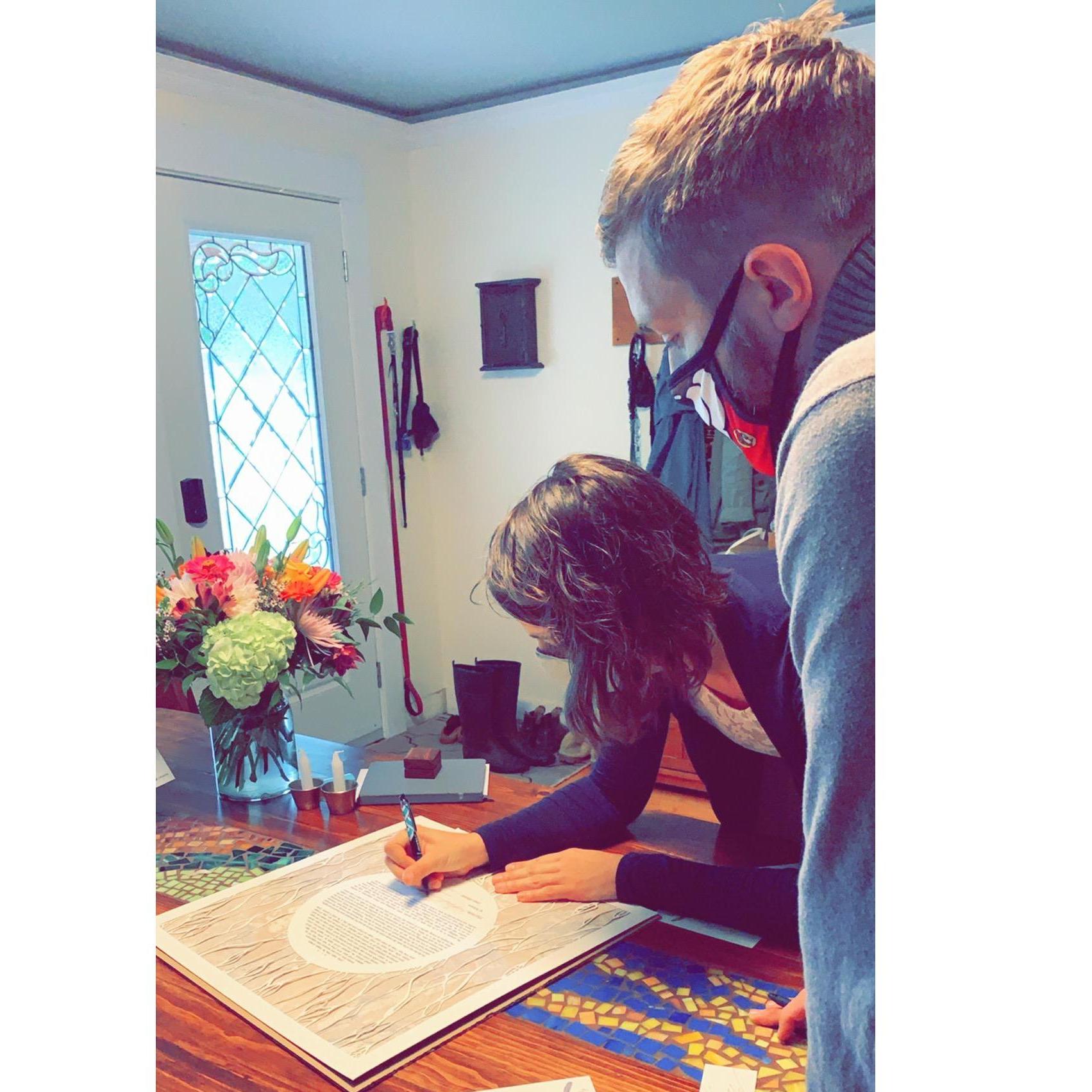 Katie signing the ketubah (with Wyatt, her brother, behind her, waiting to sign as witness).