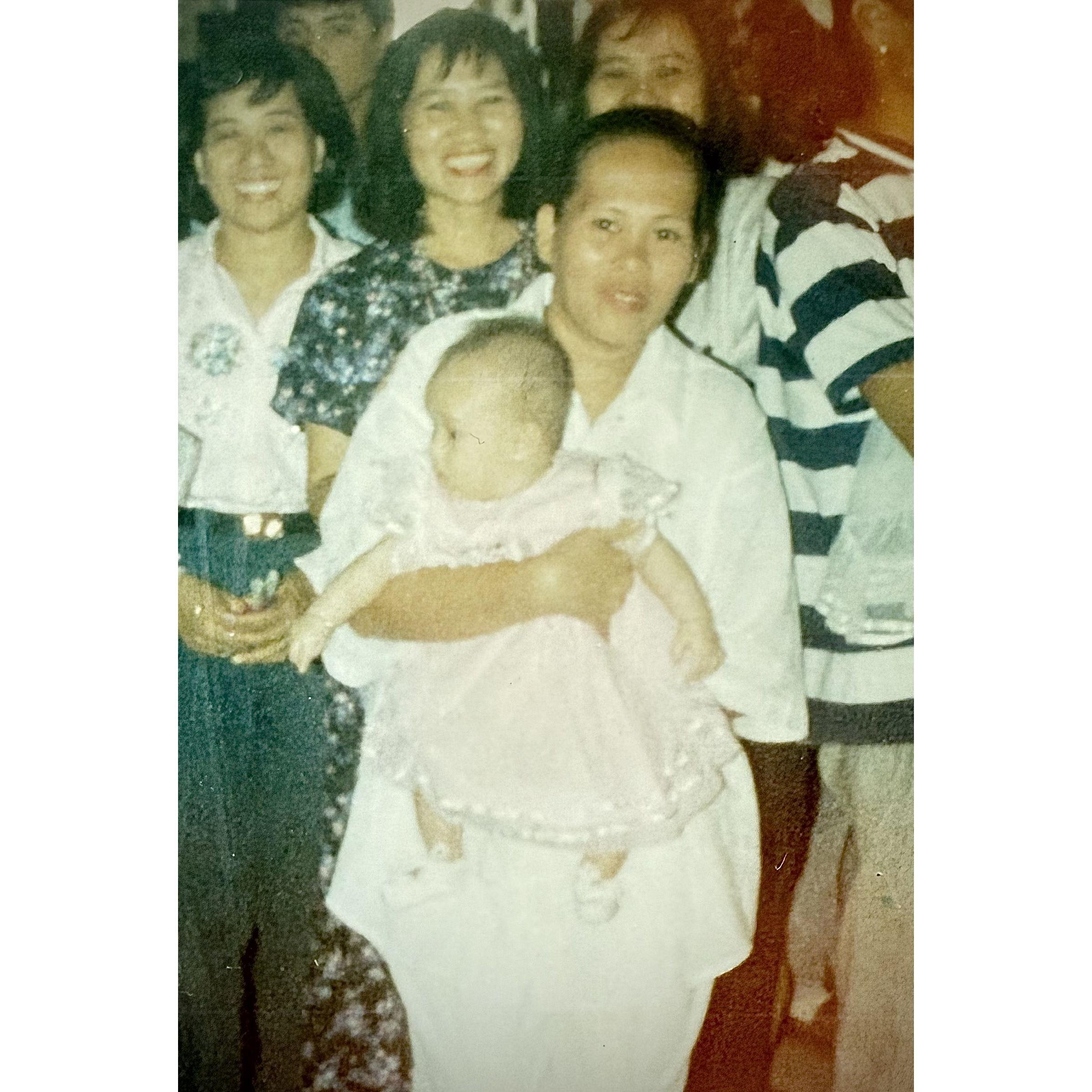 Sandra's mom holding her. But look at her three fairy godmothers in the back!