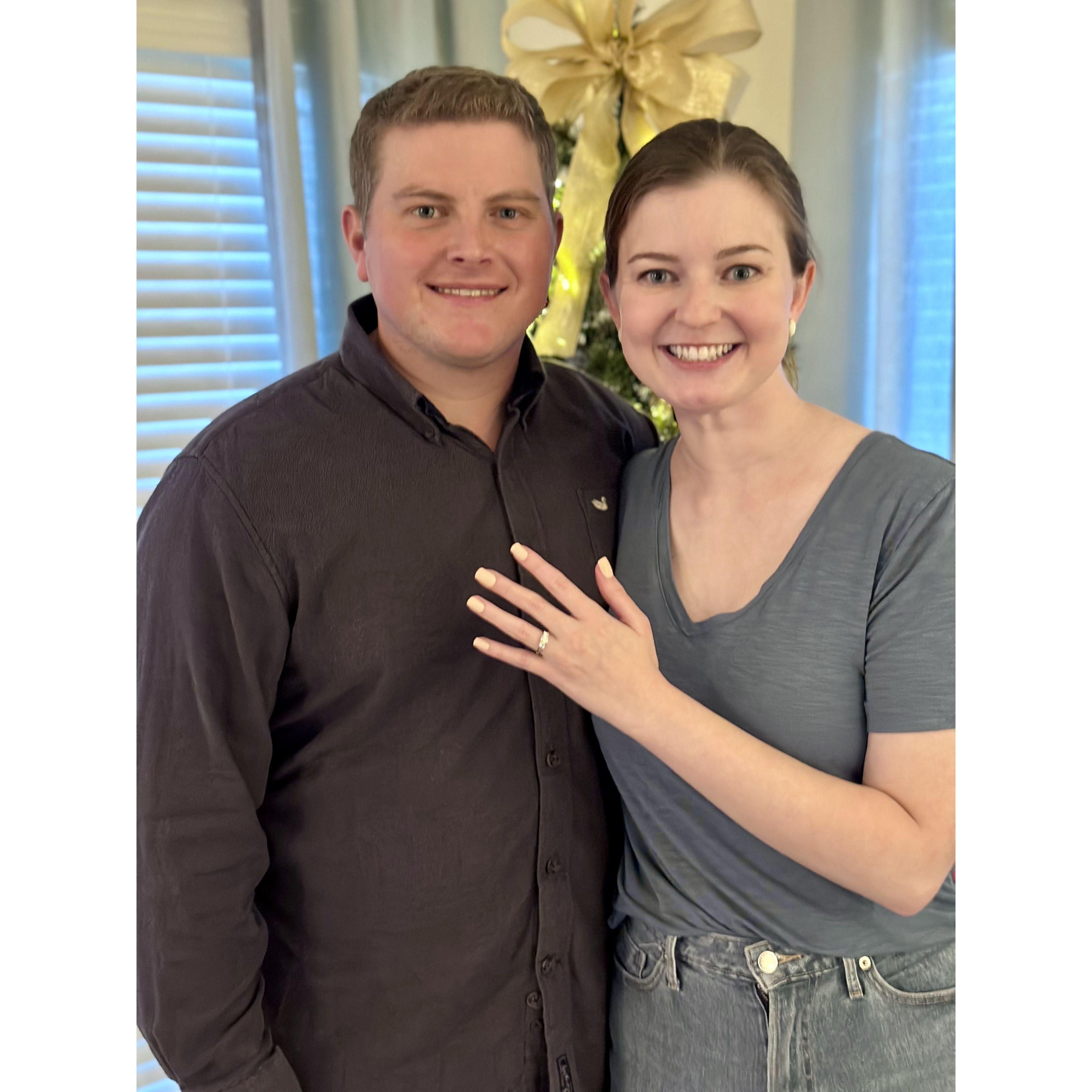 Kevin proposed to Caroline at her apartment as they were decorating for Christmas. He presented Caroline with a custom ornament to commemorate their engagement before getting down on one knee!