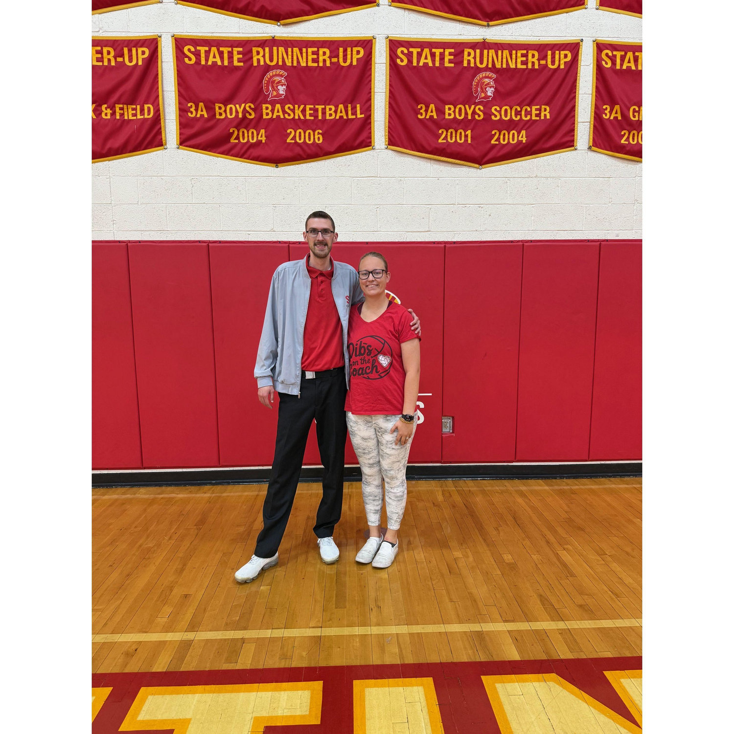 Michaela's shirt says "Dibs on the coach". Trevor is coaching for Seton Catholic Boys Volleyball.