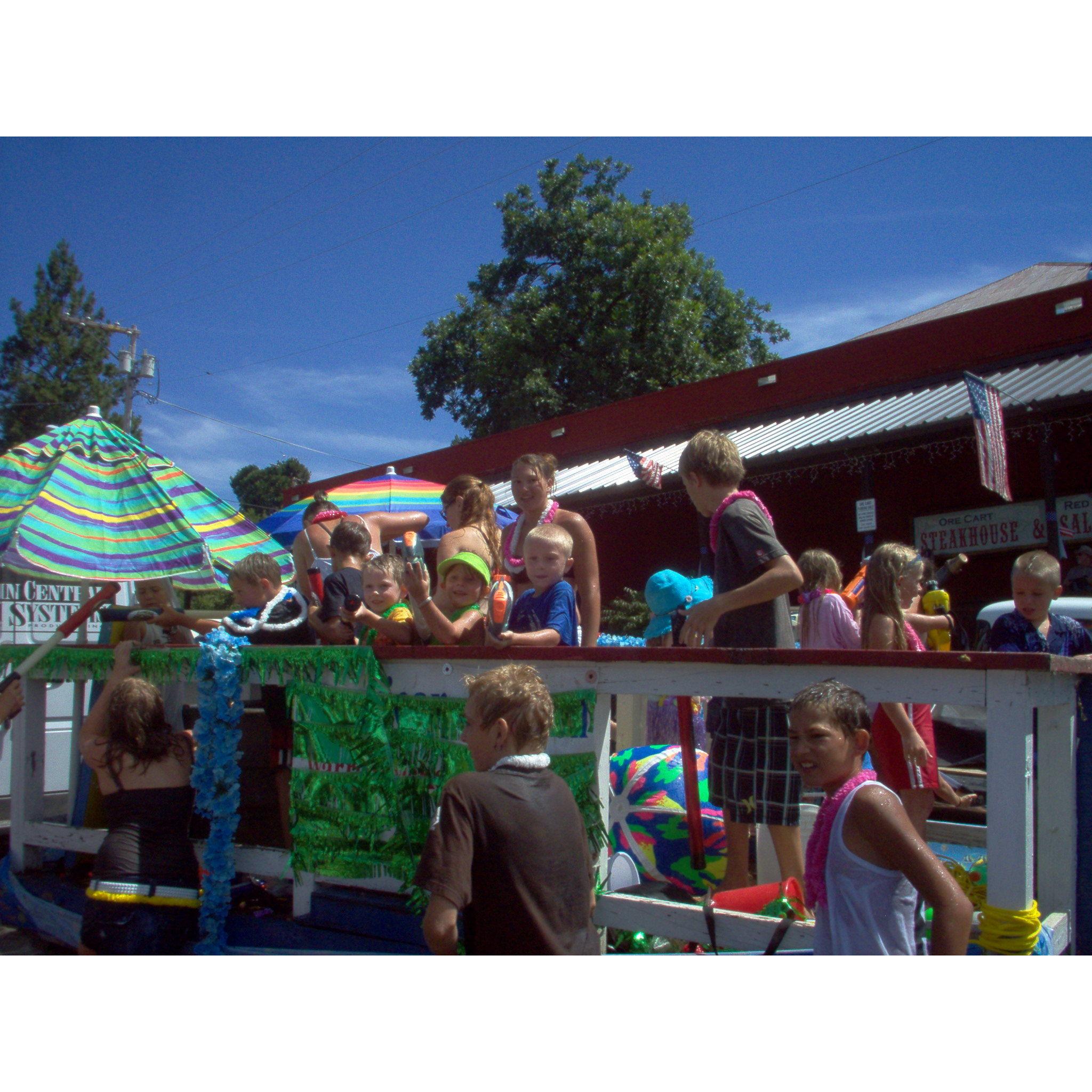 Little Cassie and Colton on the swim team float squirting people with squirt guns!