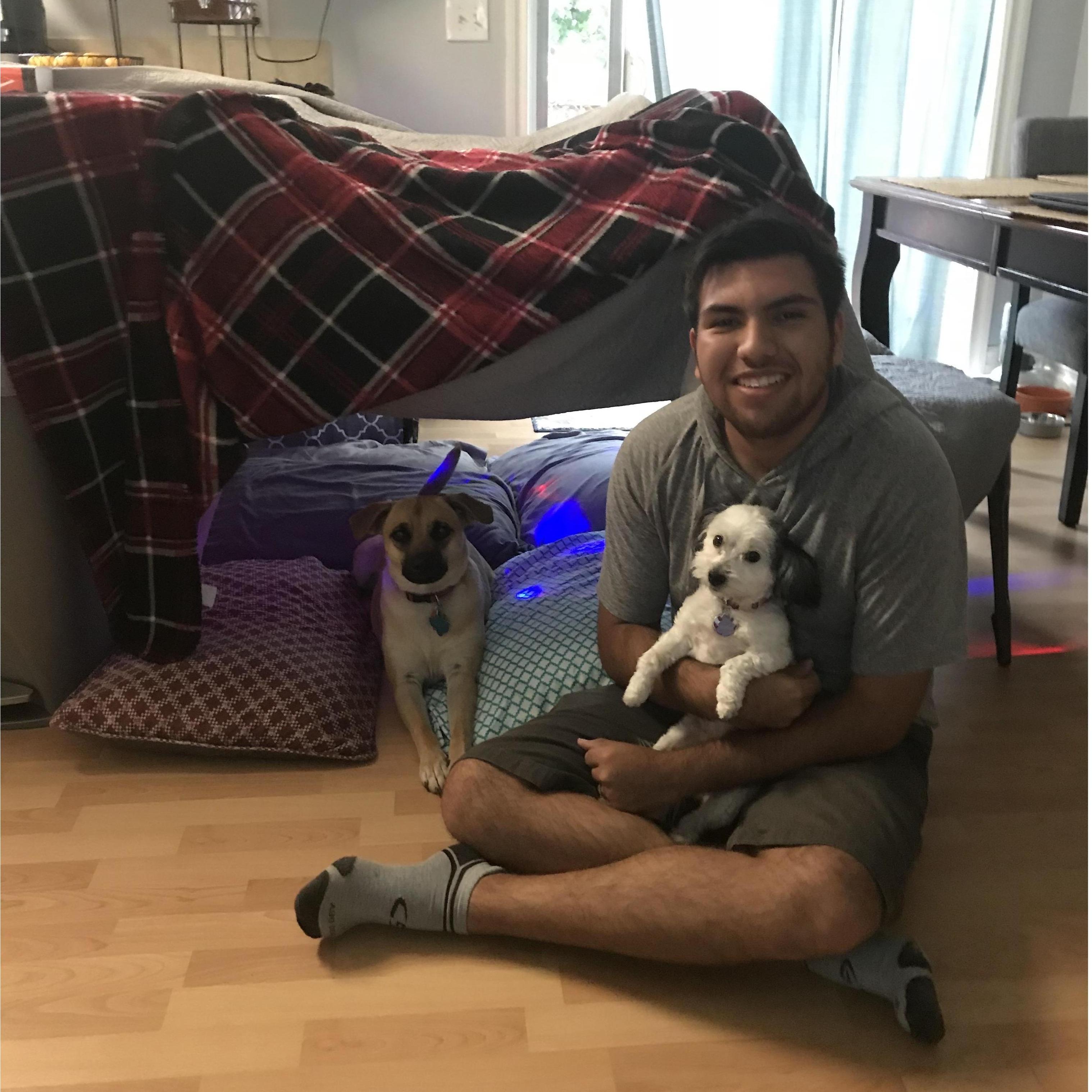 Noah being a sweet dog dad next to a pillow fort.