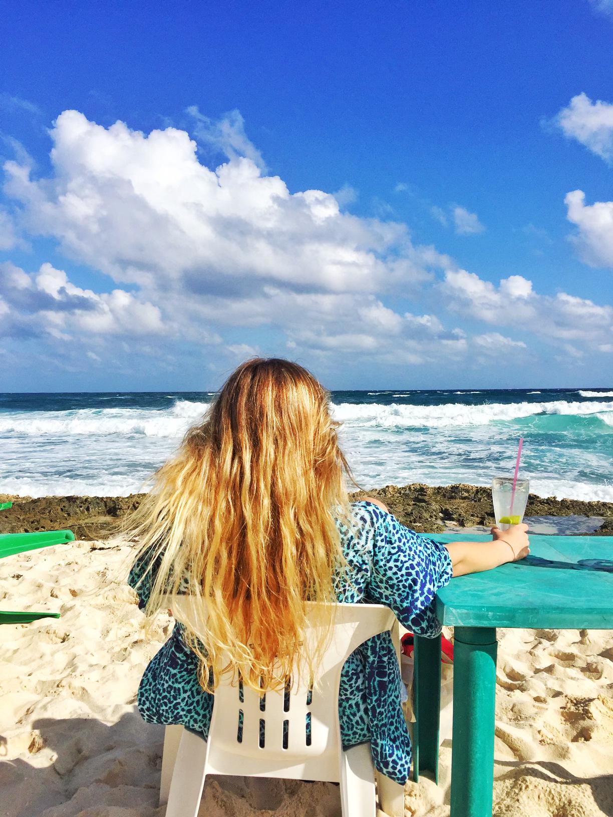 Kelly enjoying the view with a tropical 🍹 in the sand