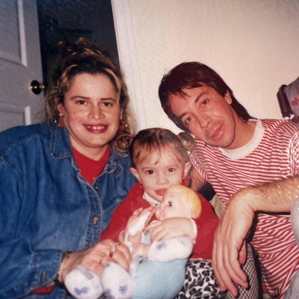 Izabella with her parents as a little girl. Mom loved putting my hair in pigtails