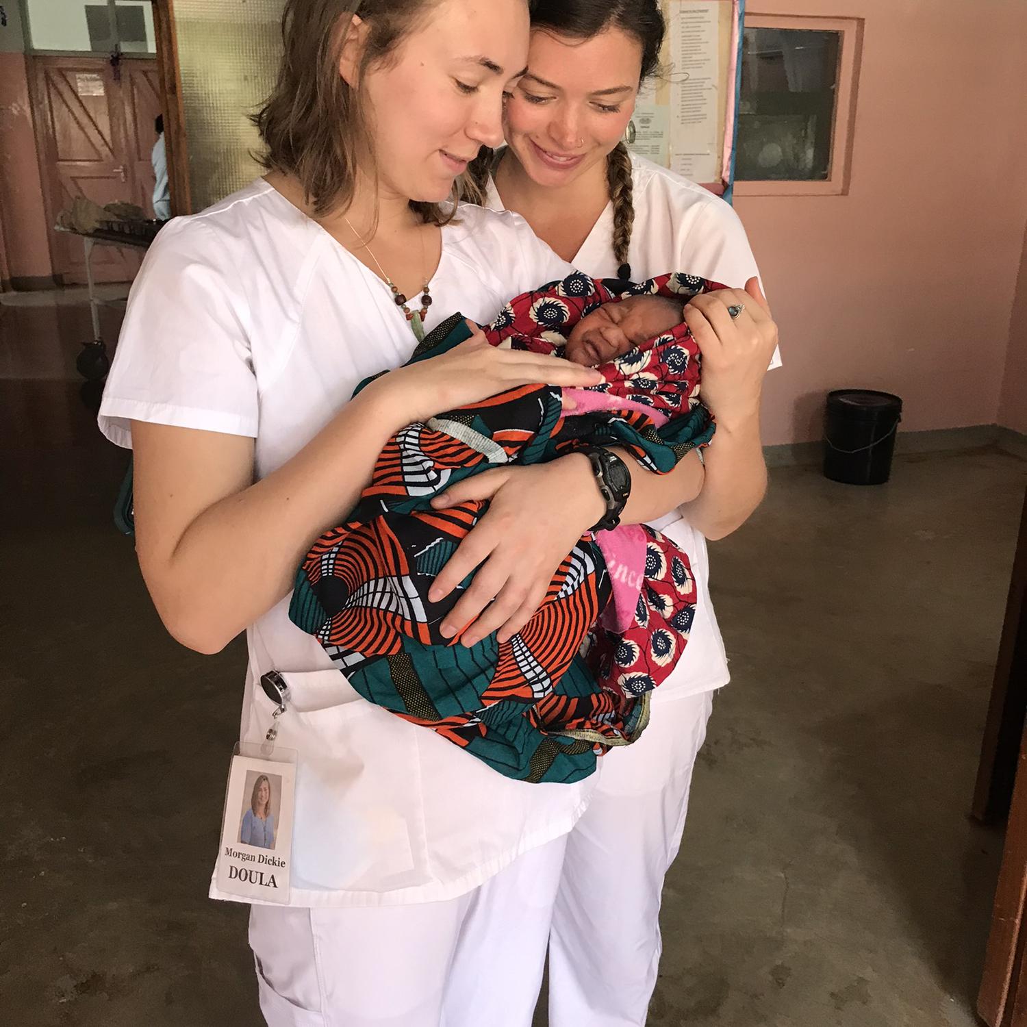 Morgan and Charlotte with baby in the clinic in Tanzania on a doula trip