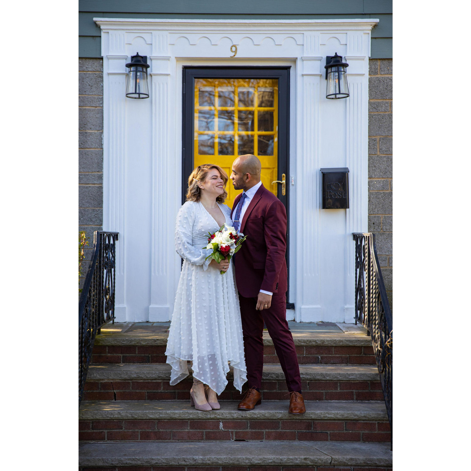 The newlyweds on the front steps of their home, where they got engaged one year before the wedding.
