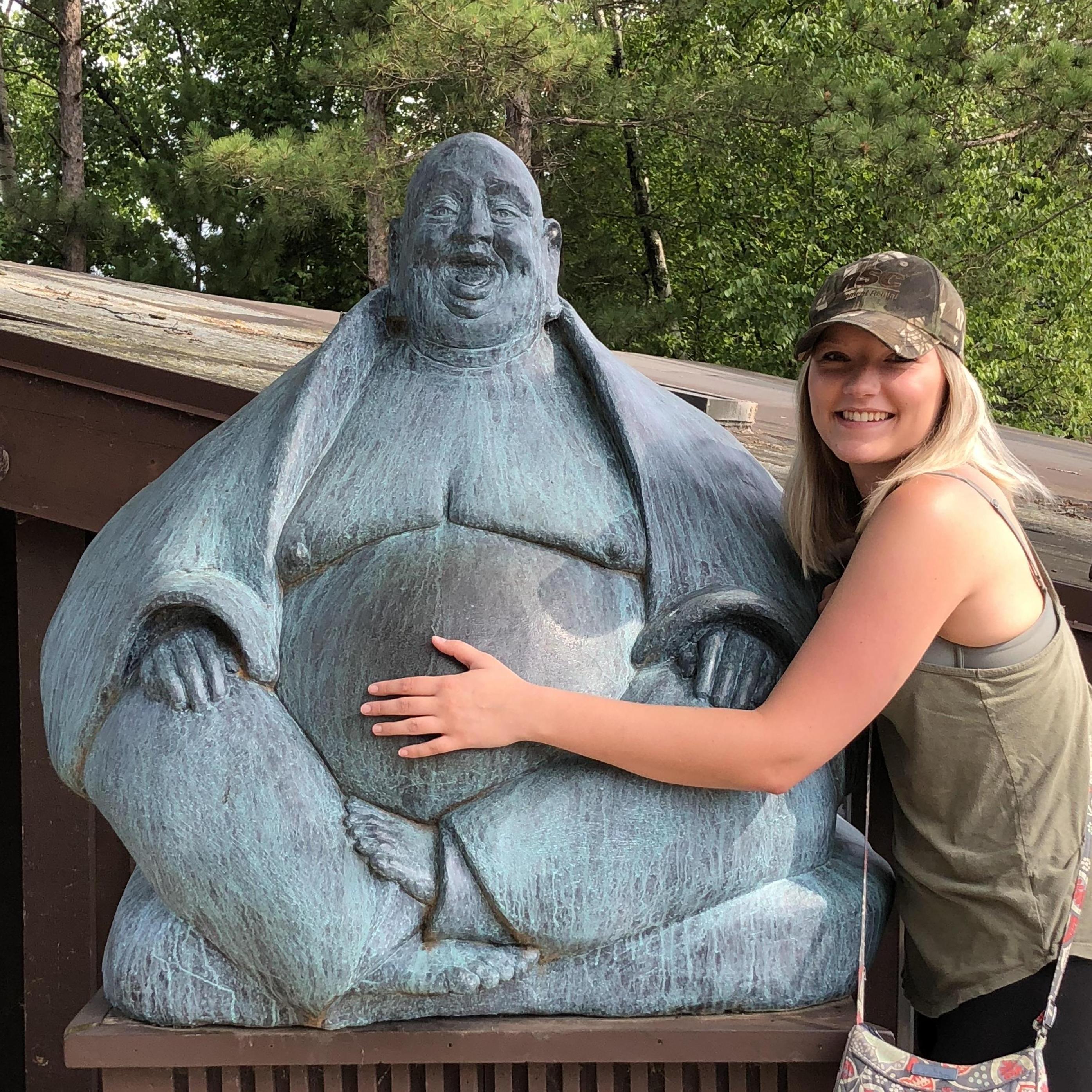 Brooke rubbing Buddha's belly for good luck at house on the rock.
