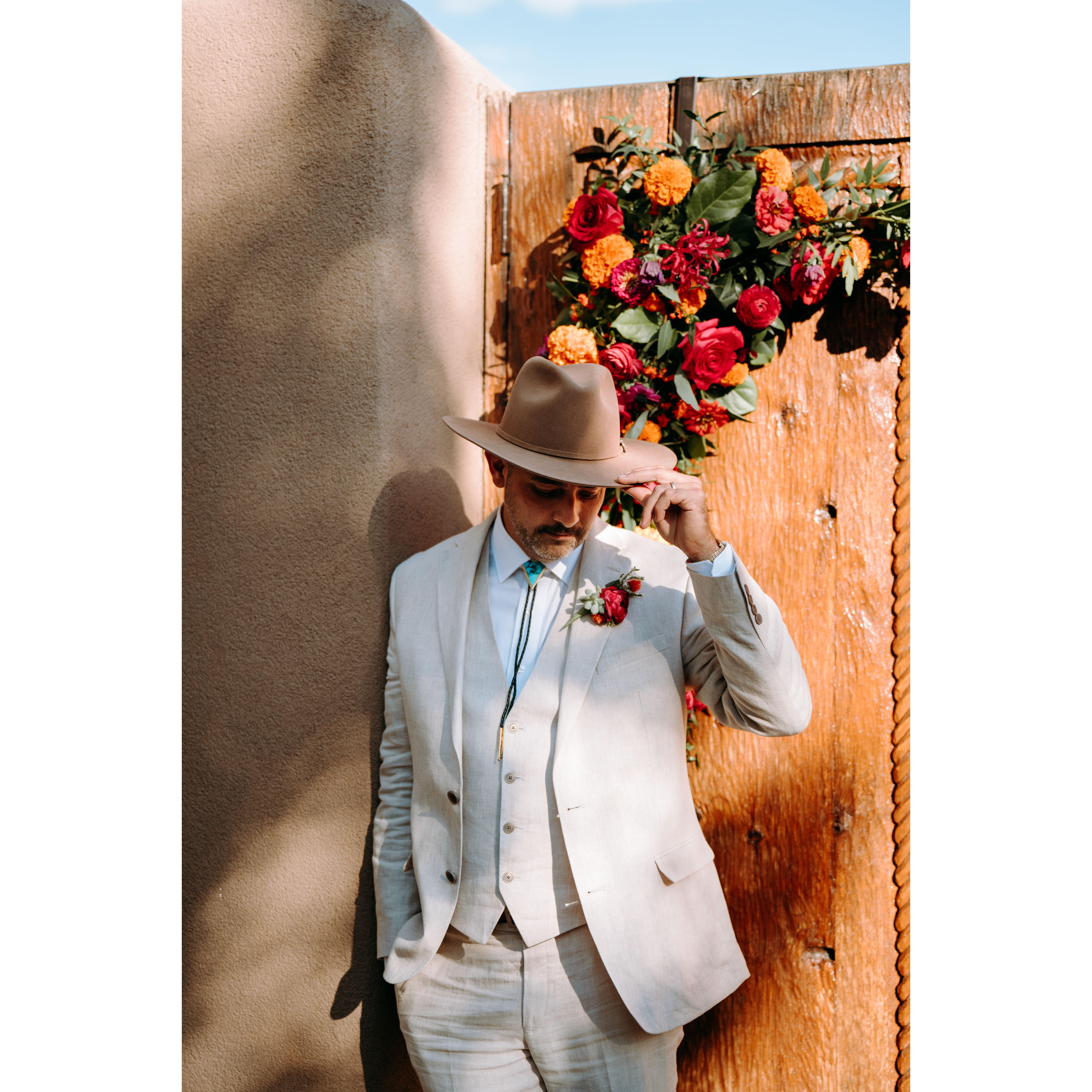 Shae tipping his hat to the camera in front of the ceremony doors inside the courtyard