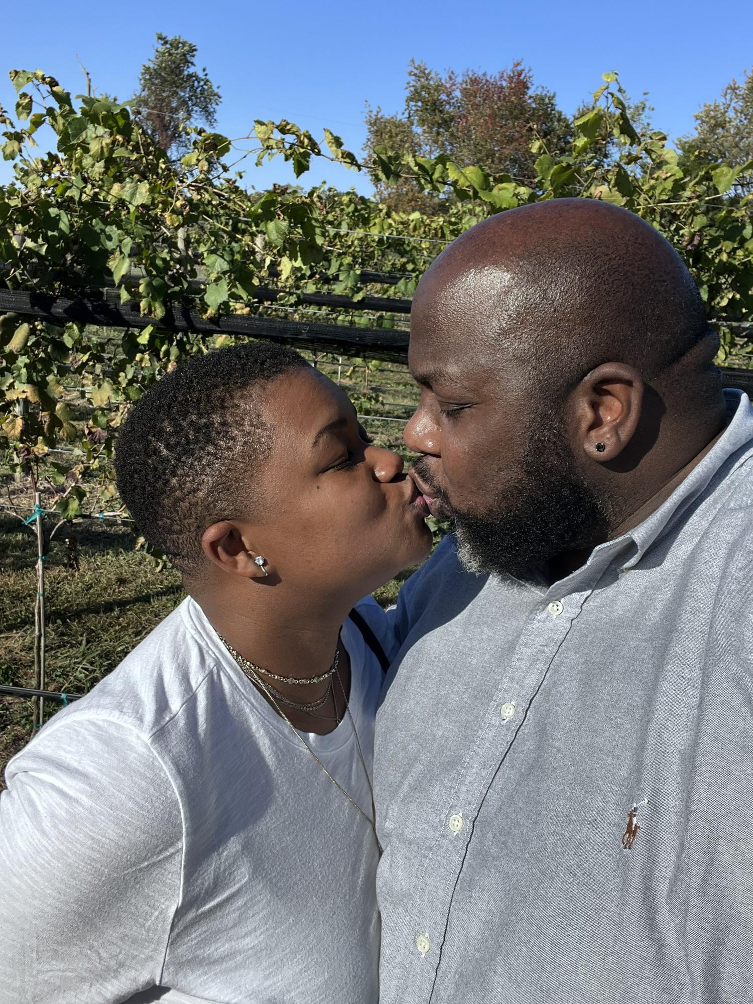Sneaking a kiss somewhere in the aisle of grapes at a winery in VA Oct 2022