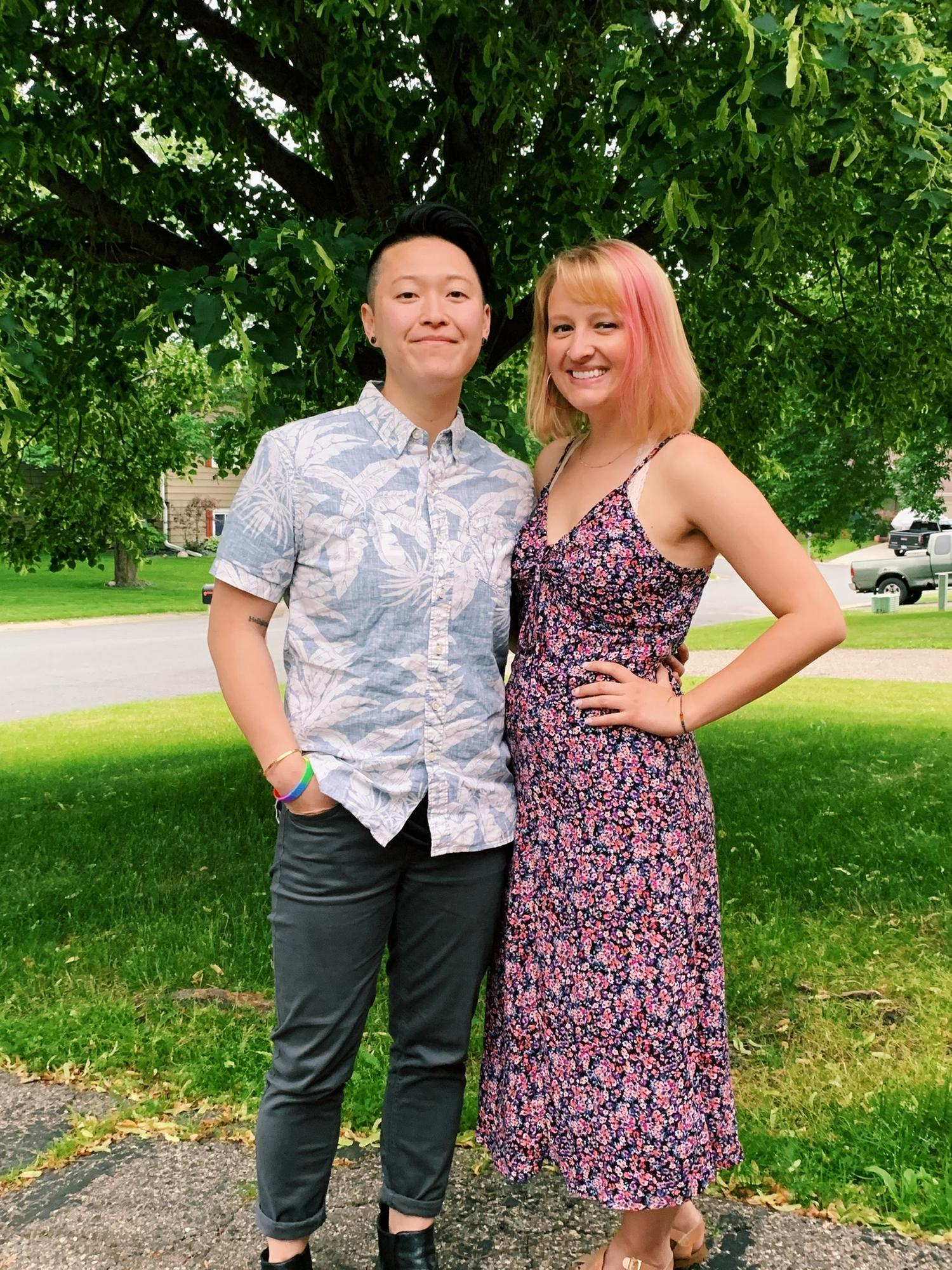 Our first visit to Anhthu’s parents house in 2019! Picture description: Anhthu and Ashley pose in a front lawn with a green tree and road in the background.