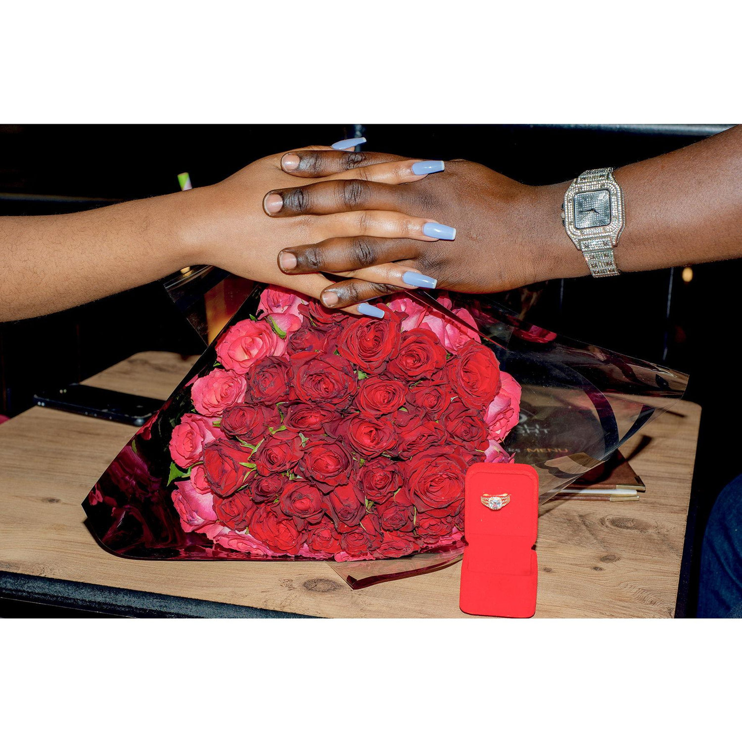 Holding hands with a ring box and a flower, hinting at the promise of a beautiful future together.