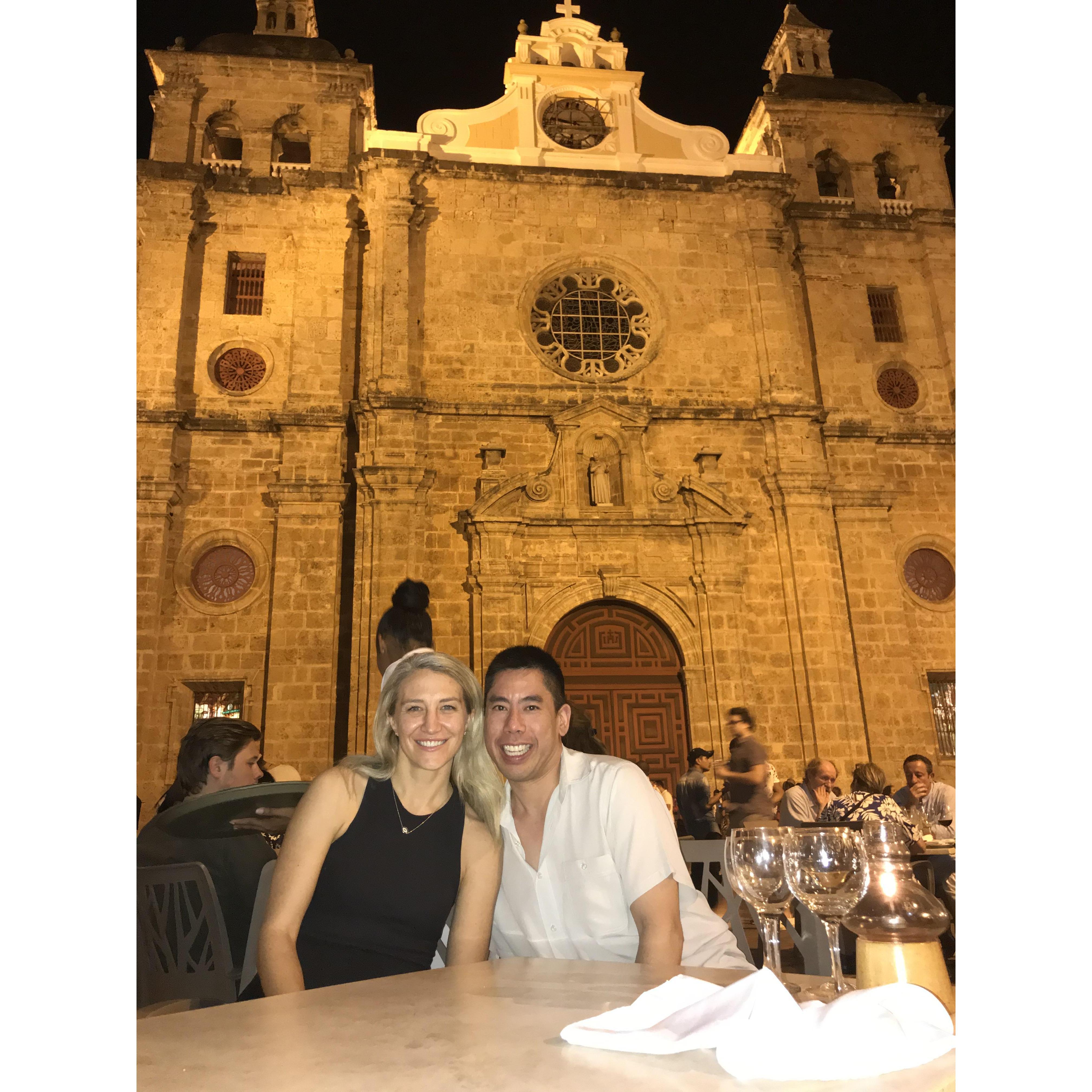 Erica and Andy in Cartagena, dining outside next to one of the town's historic churches.