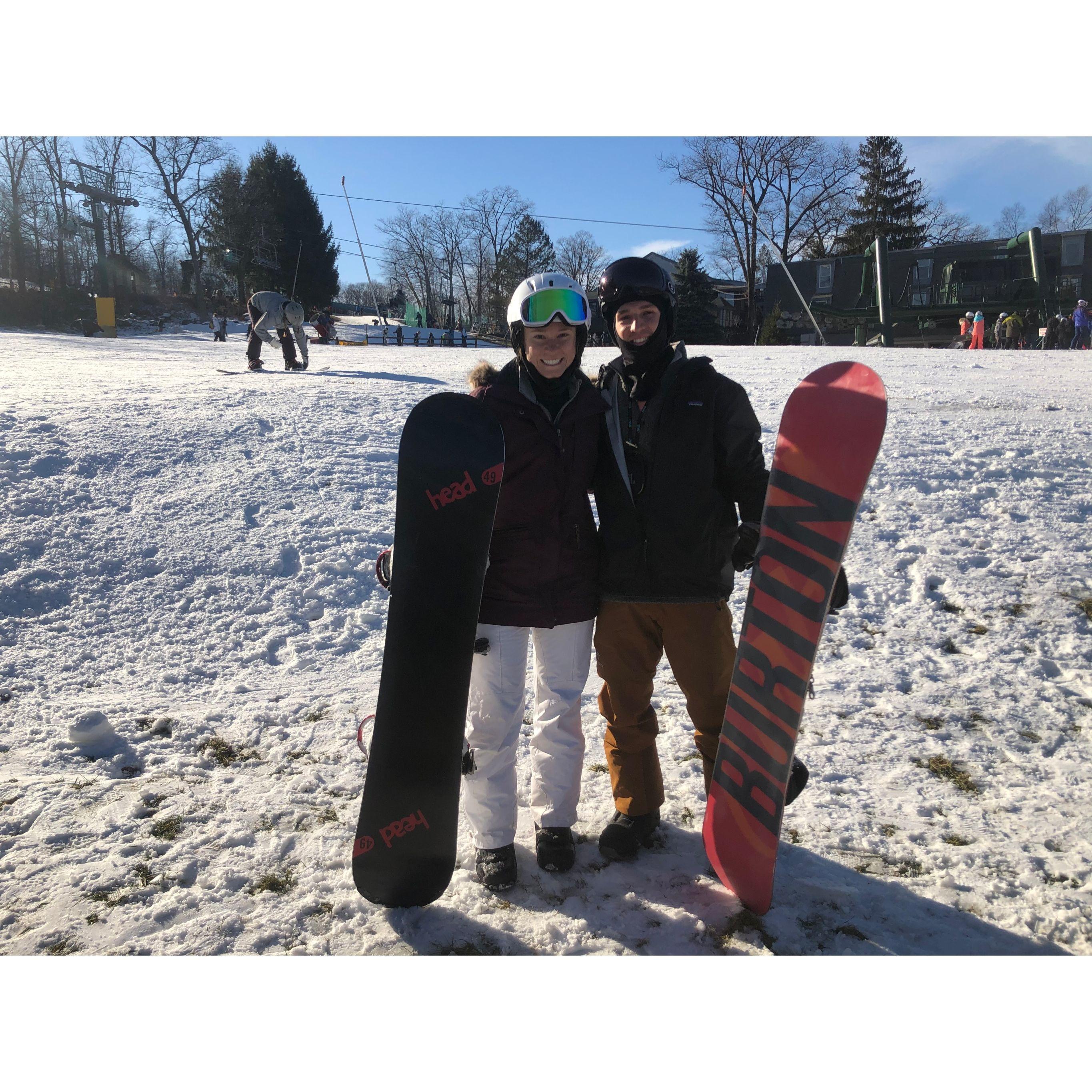 Tanner attempting to teach Meg to snowboard