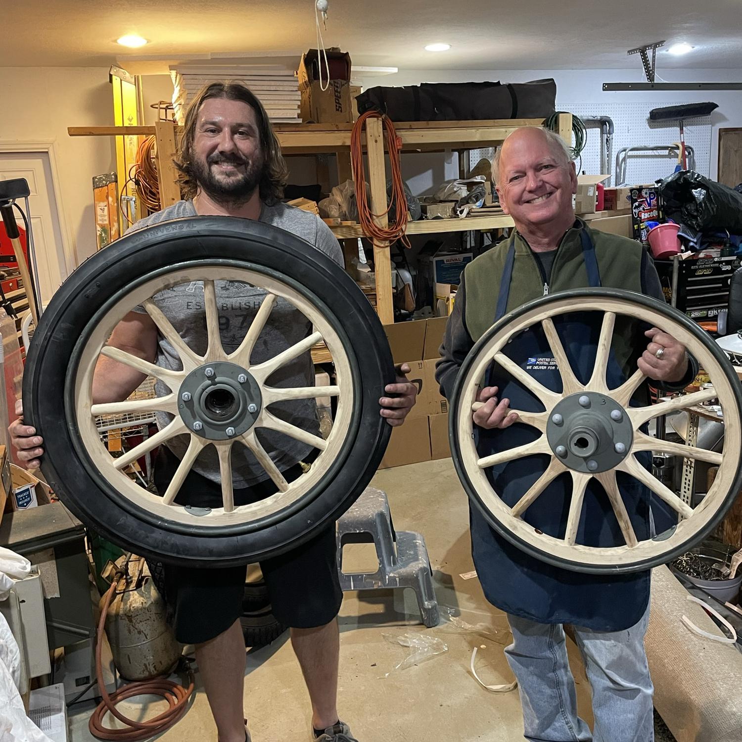 David and my Dad holding the wheels of the 1907 Cadillac- before and after tires