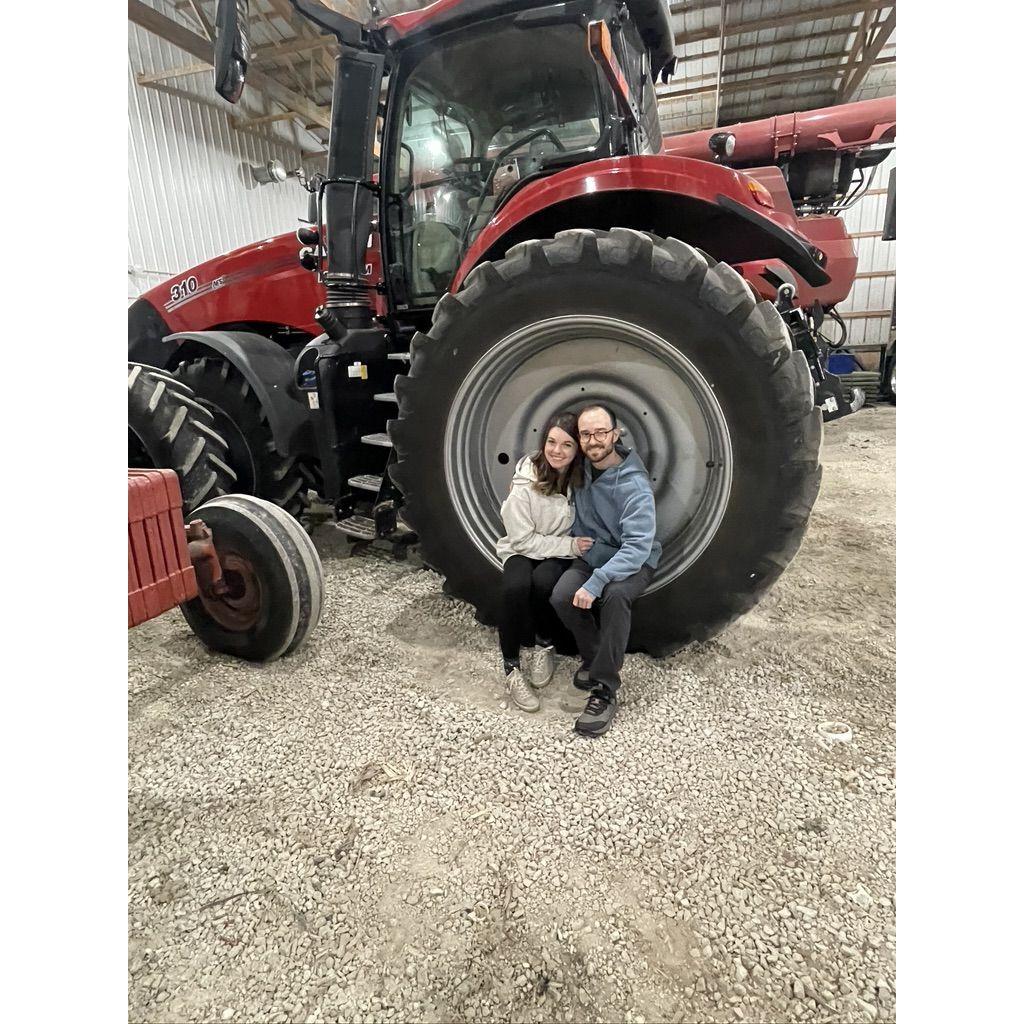 Traditional Clayton family couple photo in the tractor wheel at the Illinois farm 