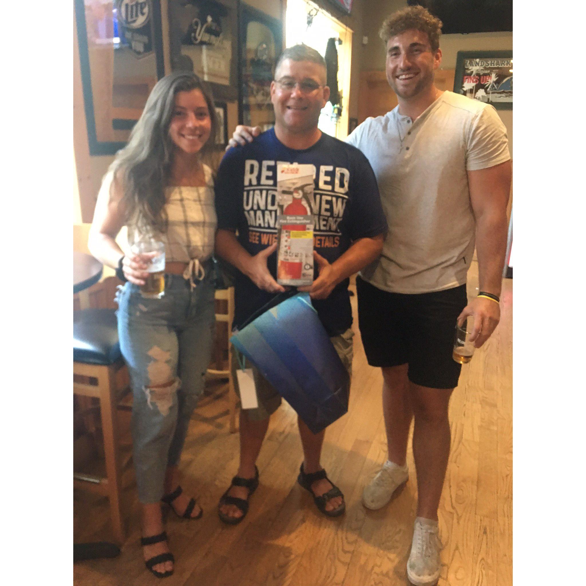 the couple with the officiant at his retirement party!