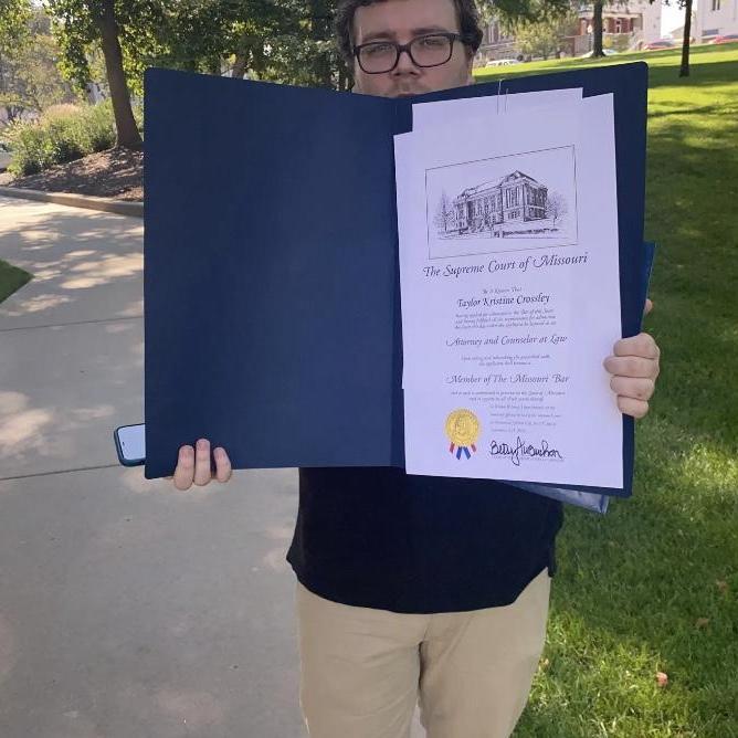 Trevor proudly displaying Taylor's Missouri bar admission certificate after her swearing in ceremony.